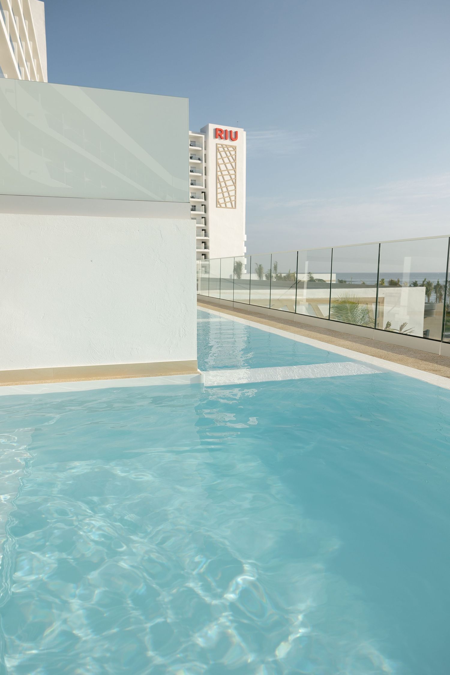 Luxury rooftop pool at RIU hotel with white architecture and clear blue water.
