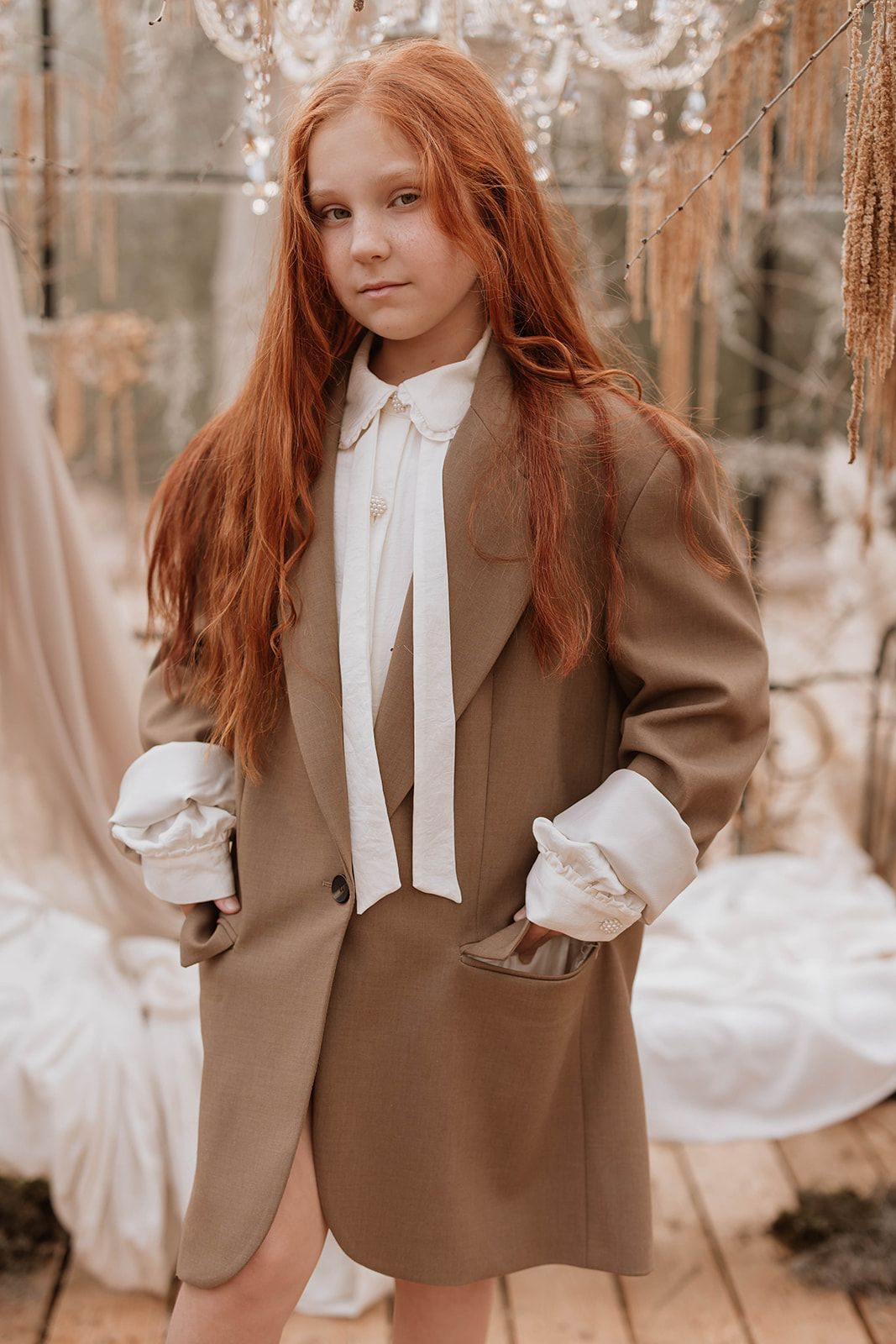 Vintage-inspired fashion shoot with brown coat and white blouse in greenhouse setting.