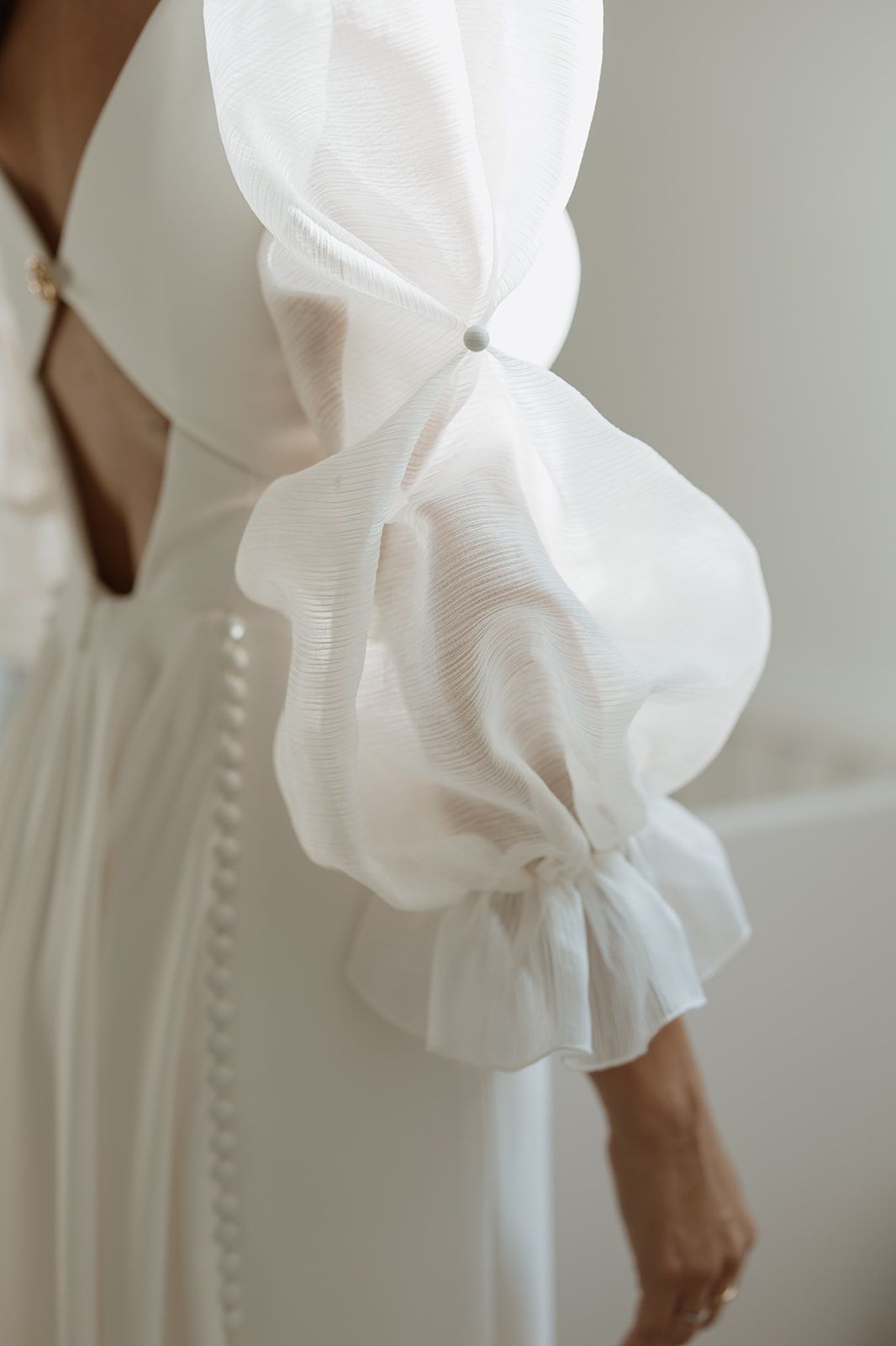 Close-up detail of white puffy sleeve with gathered fabric on wedding dress.