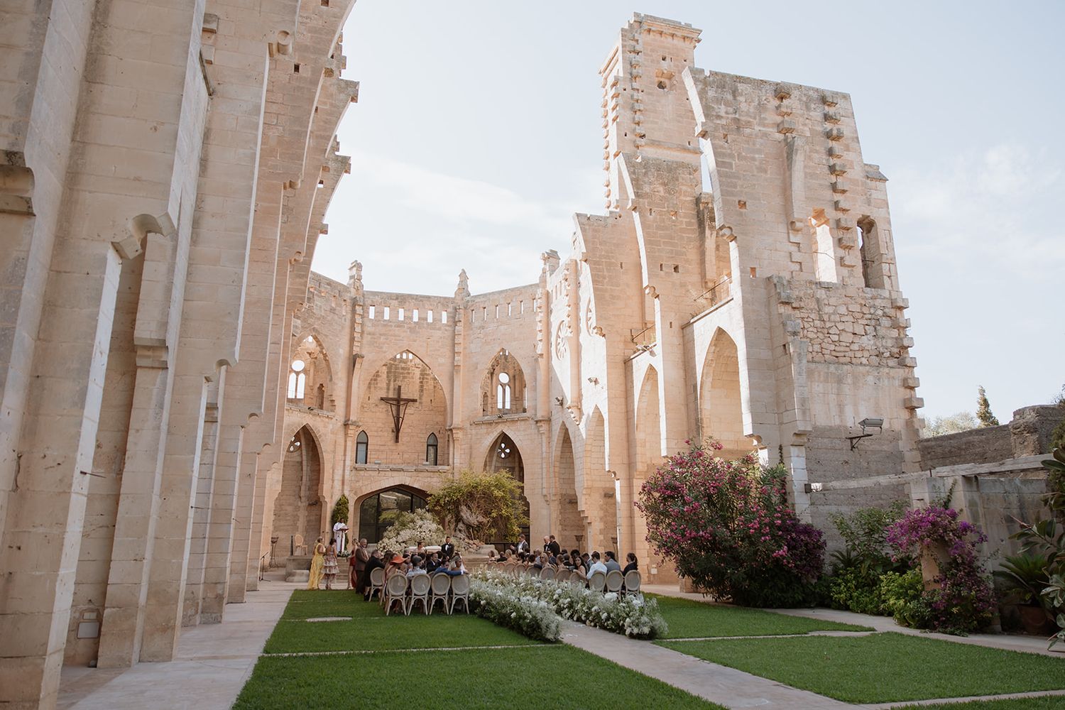 Stone cathedral ruins with gothic arches hosting an outdoor wedding ceremony setup.