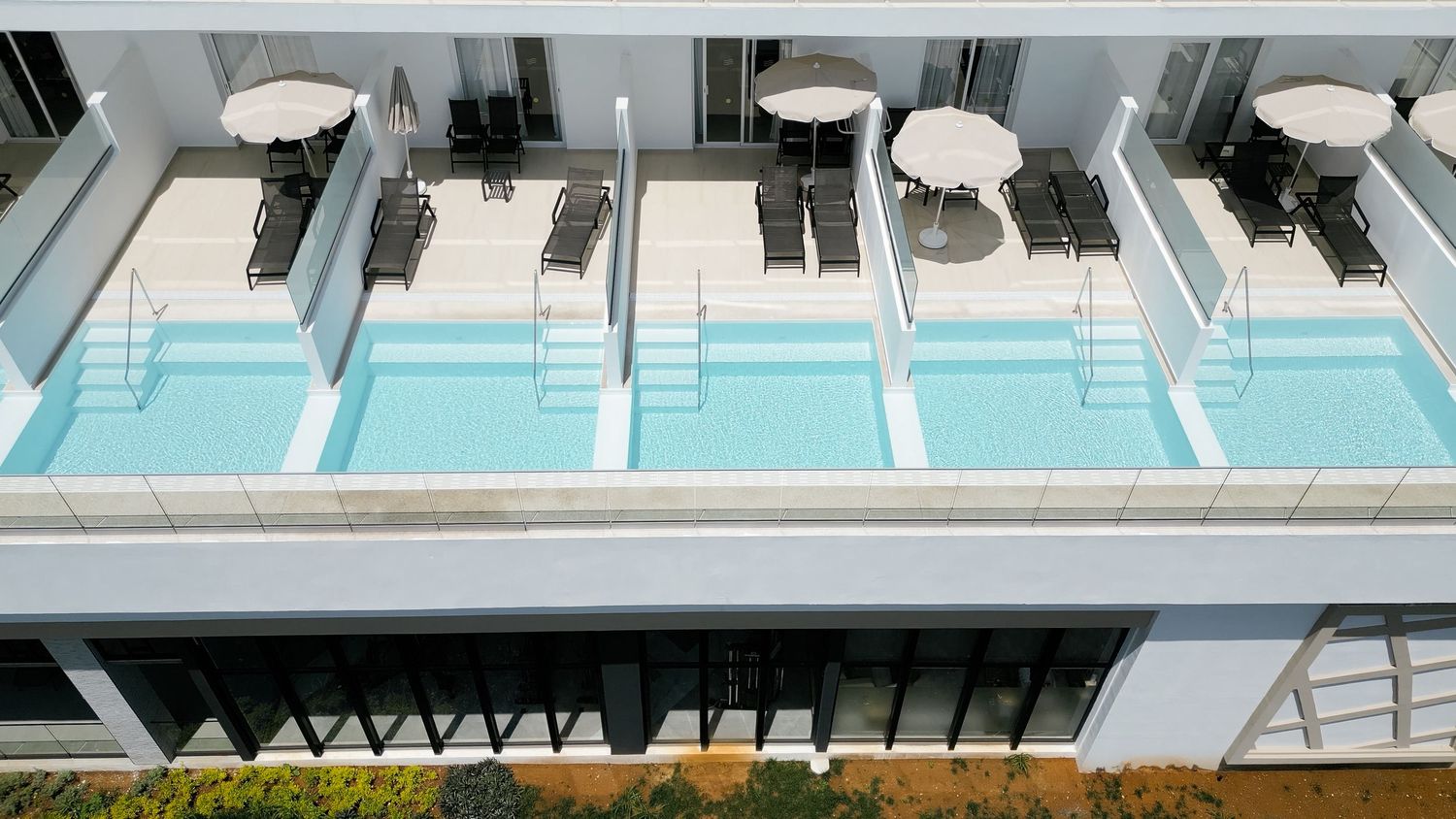 Luxury hotel swim-up rooms with private pools and white umbrellas on individual balconies.