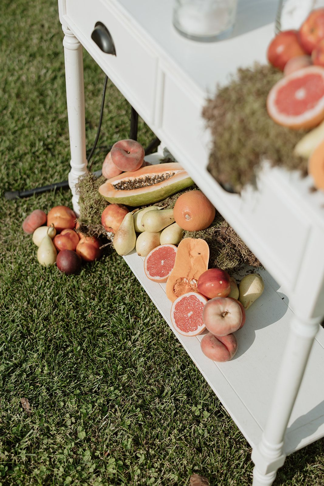 Fresh fruit display with grapefruit, apples, and tropical fruits on a white vintage table.