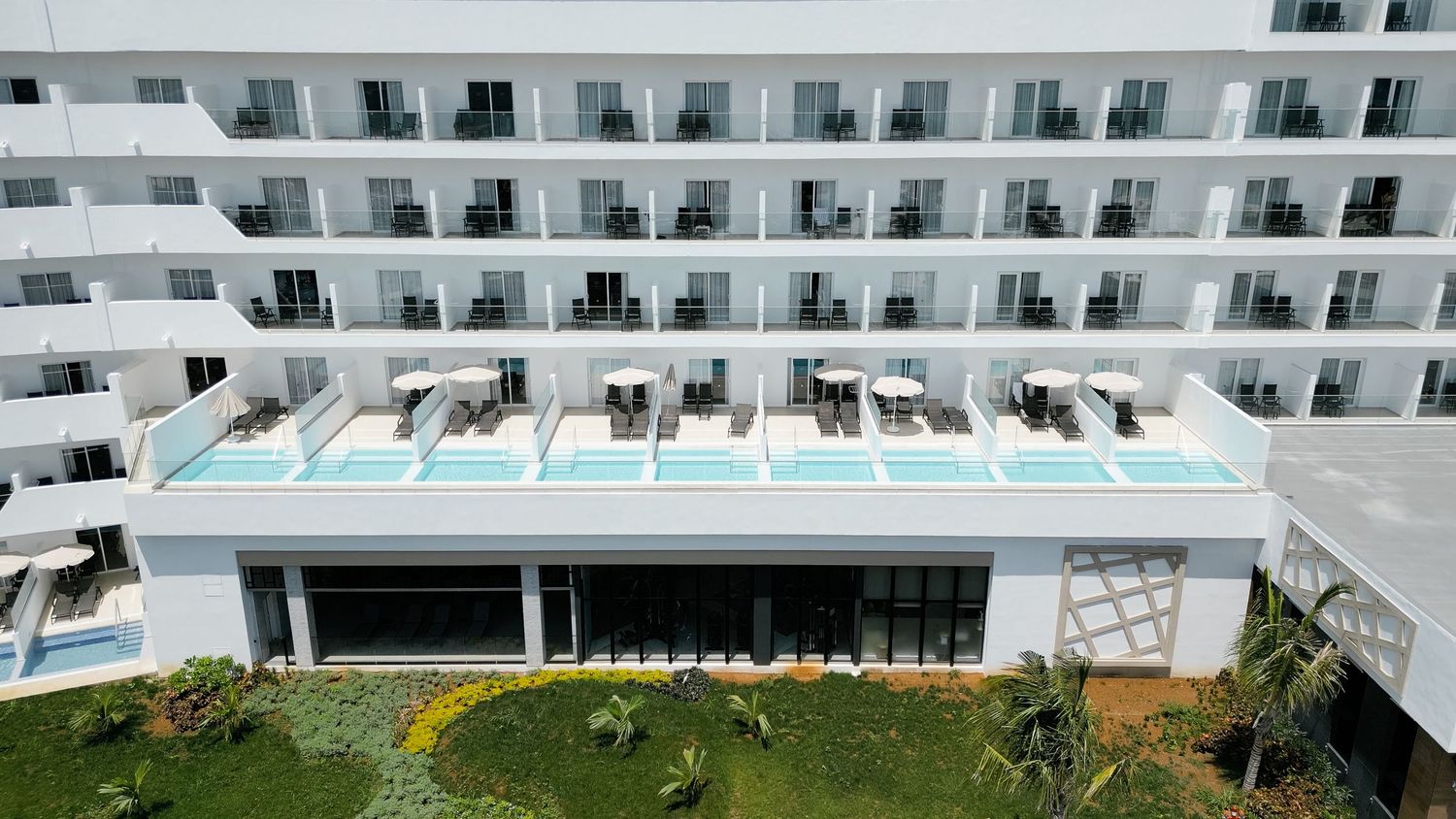 Luxury resort building with multiple floors of balconies and a rooftop swimming pool area.