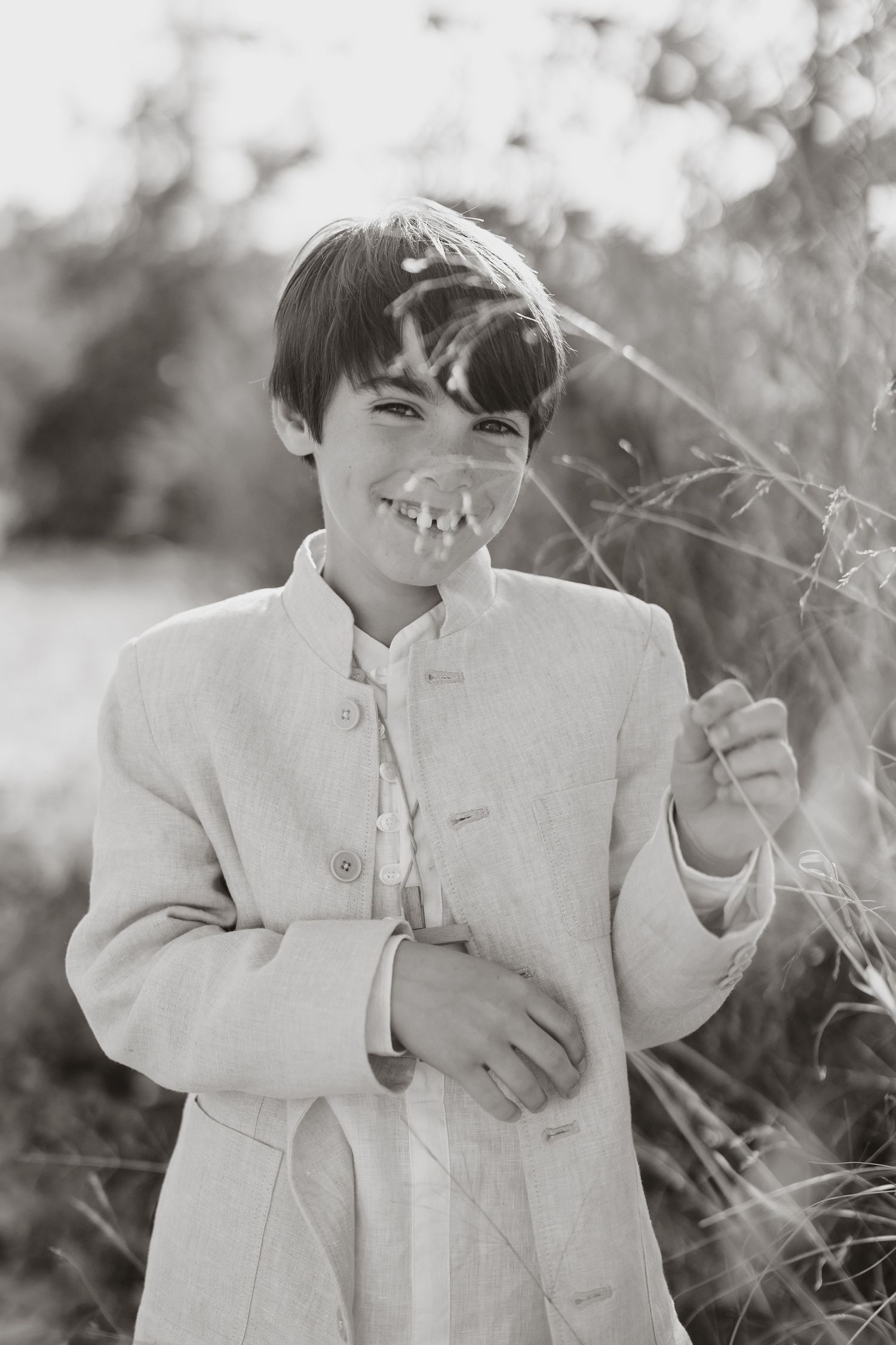 A joyful moment captured in black and white as a child in a white coat plays outdoors.