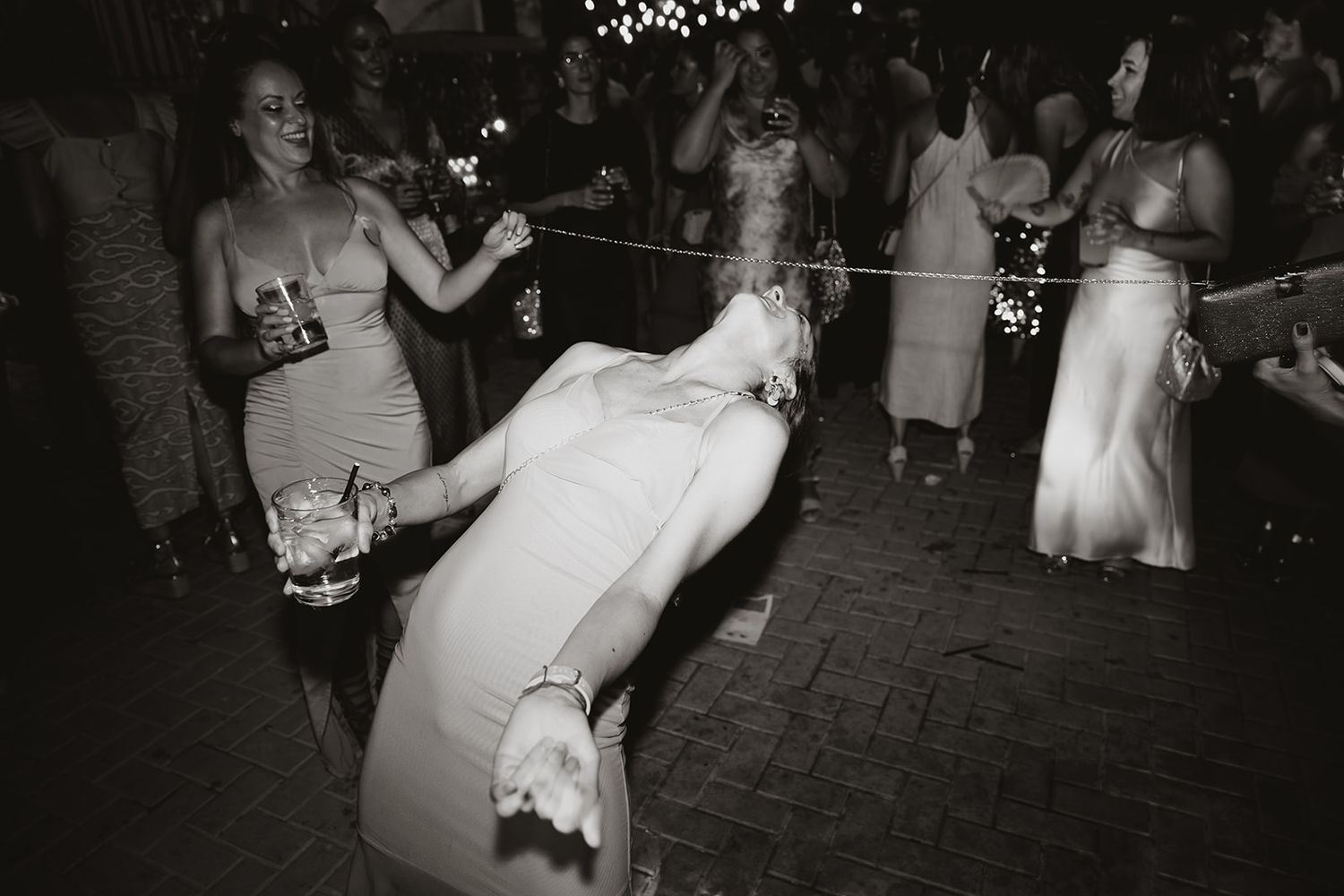 Wedding reception dance floor filled with guests celebrating under dim lighting.