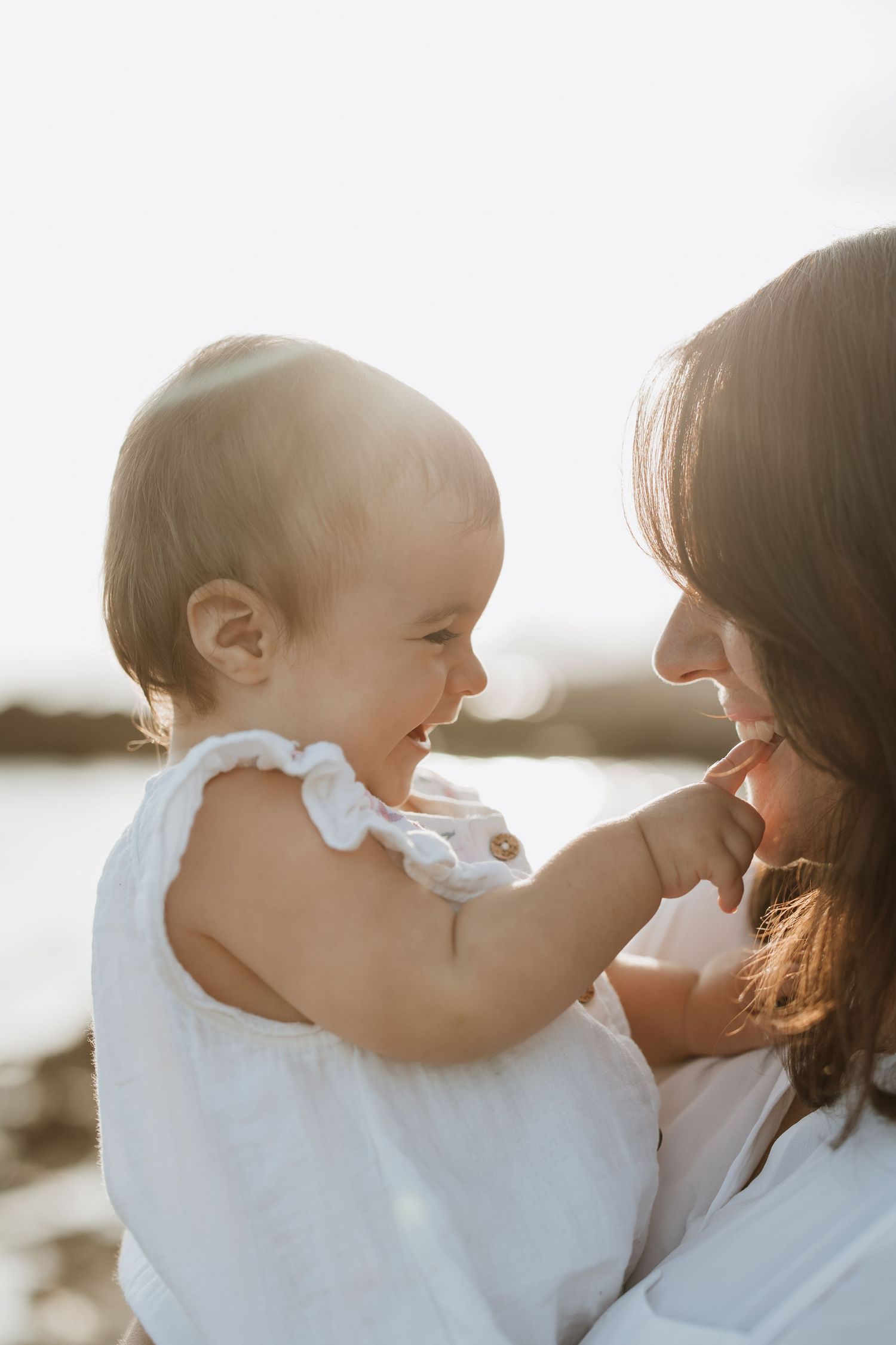 Joyful laughter shared between caregiver and baby during intimate outdoor photoshoot.