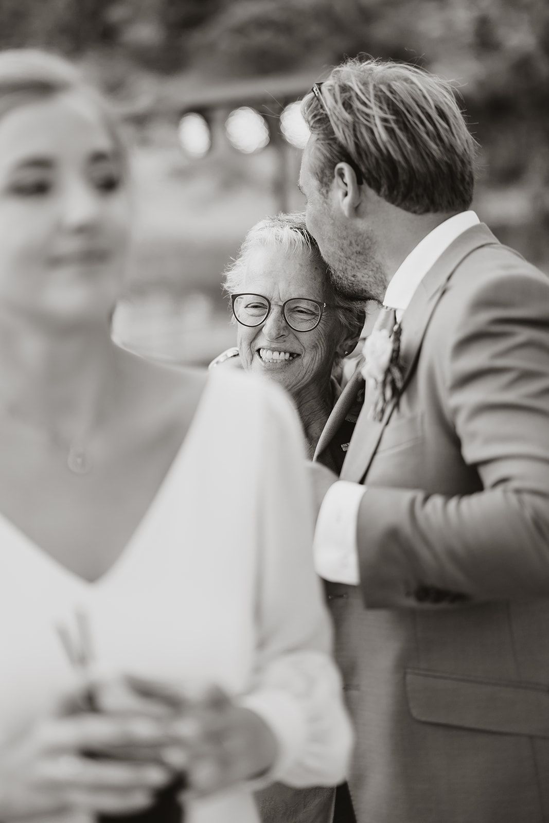 Black and white candid moment at wedding reception with guests laughing.