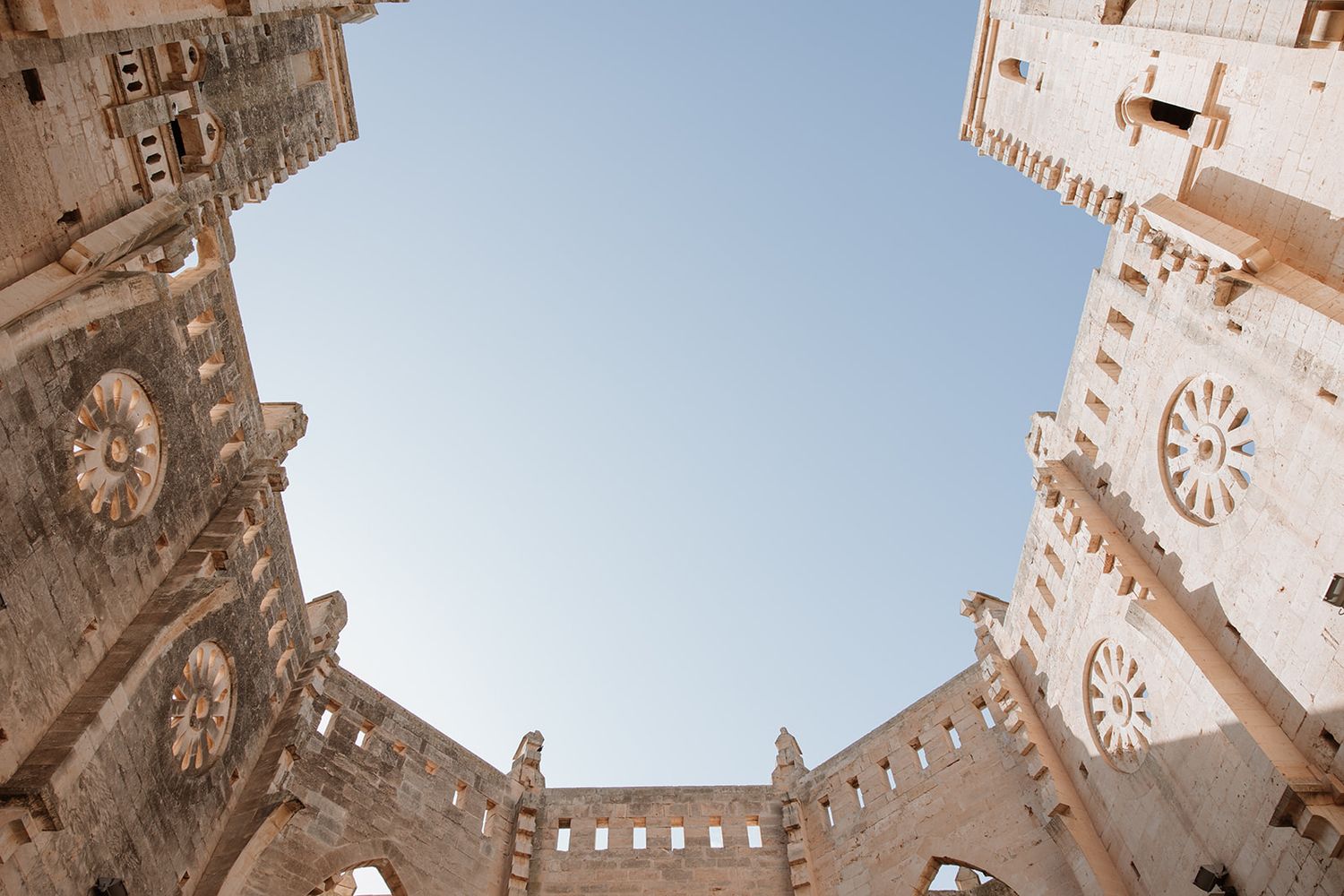 Upward architectural view of gothic cathedral towers against blue sky.