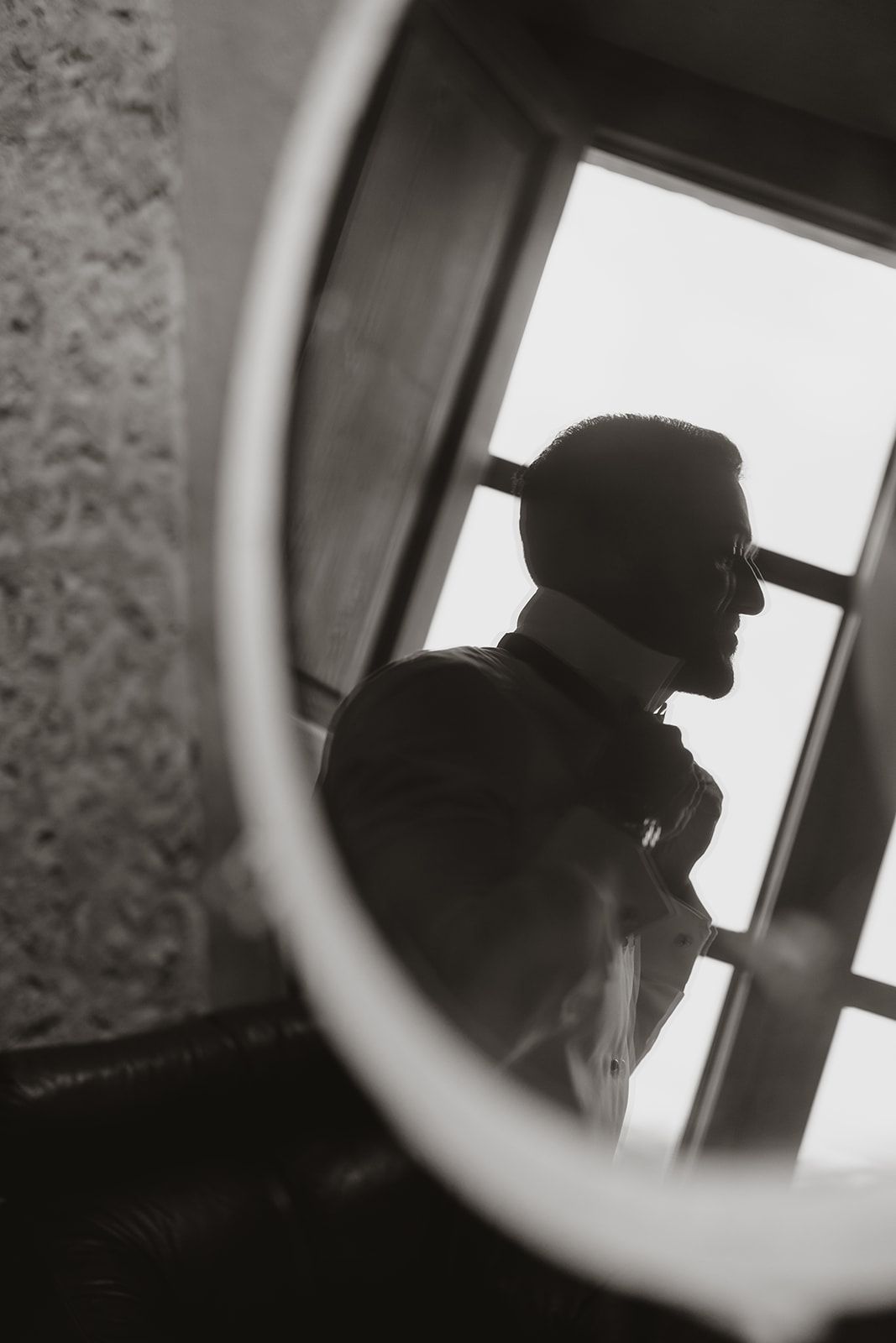 Artistic black and white silhouette reflection in mirror of person wearing a cap.
