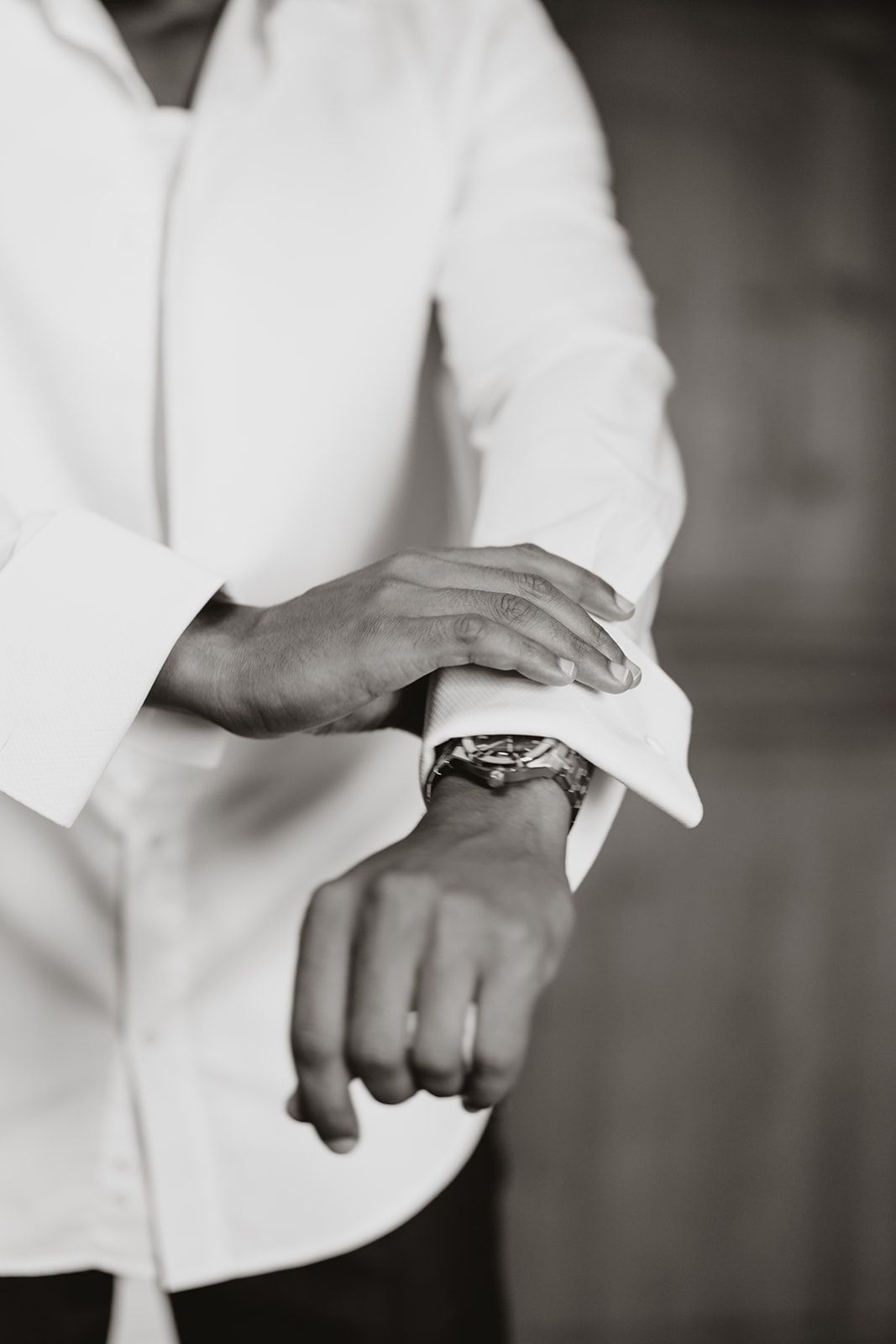 Close-up of hands adjusting formal white shirt cuffs.