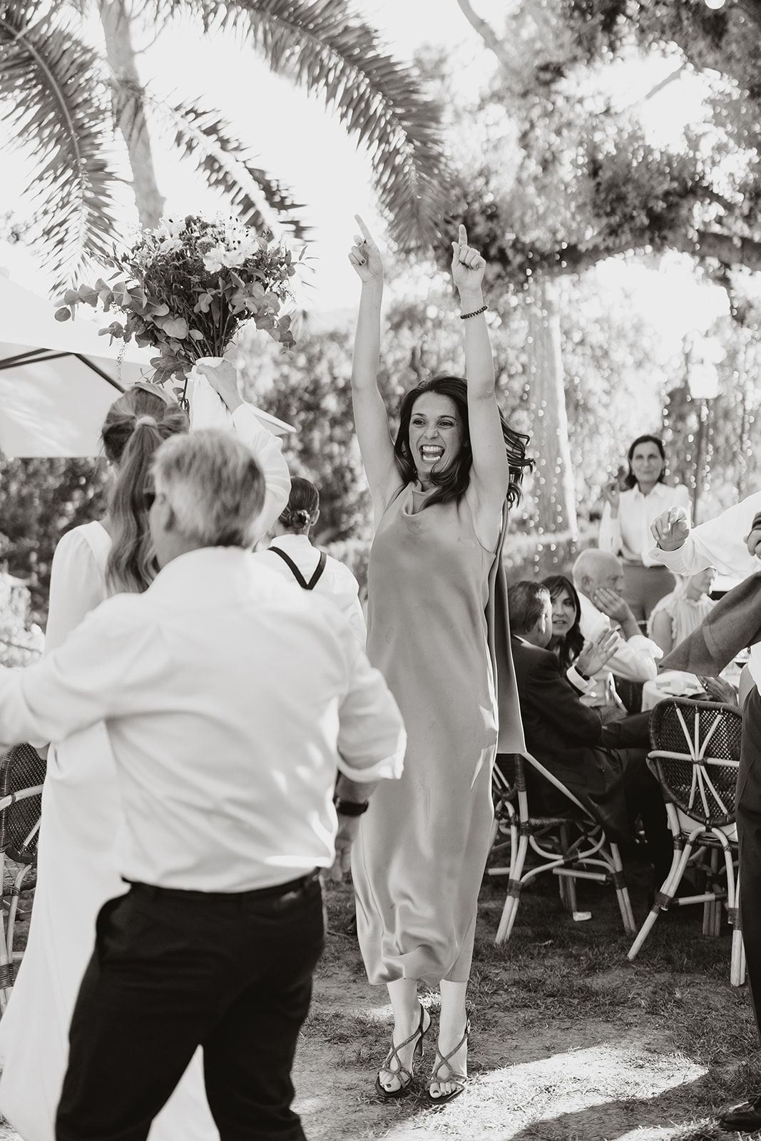 Wedding celebration with joyful dancing under palm trees.