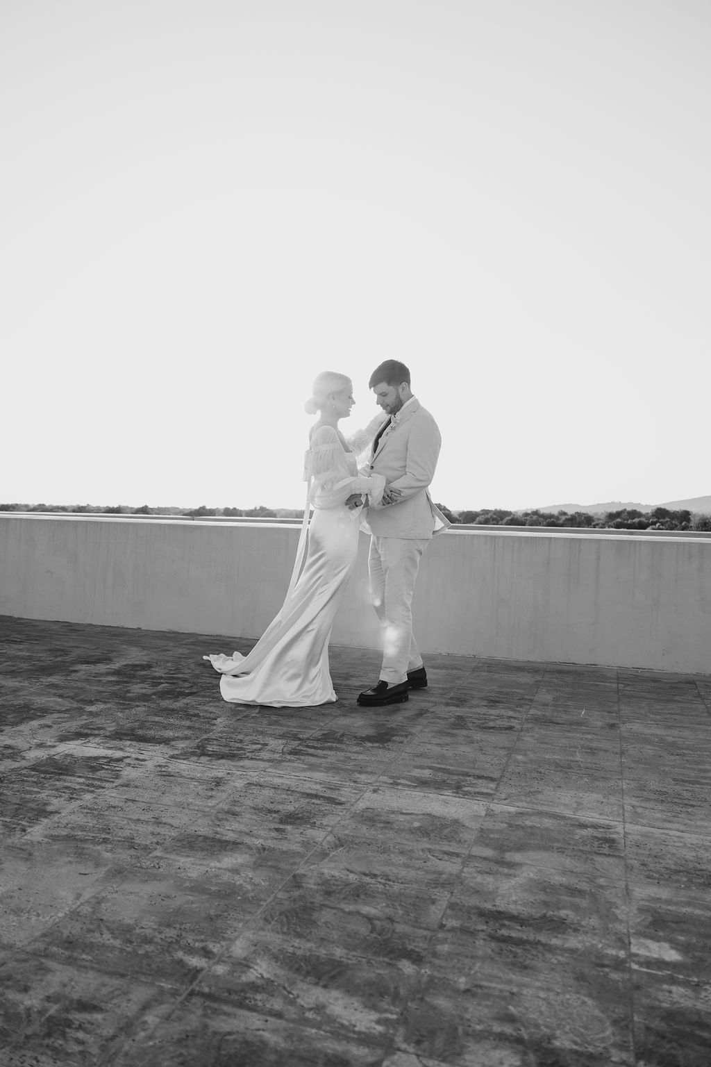 Black and white wedding photo showing couple's intimate rooftop moment.