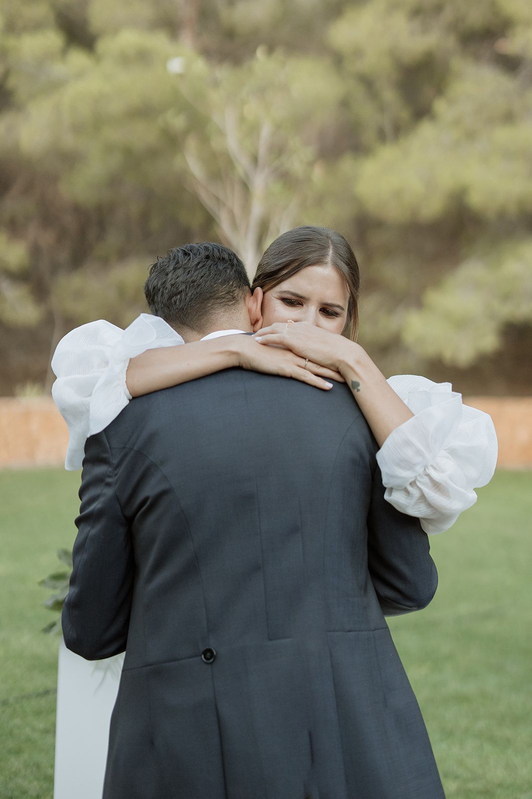 A tender embrace between newlyweds in a garden setting.