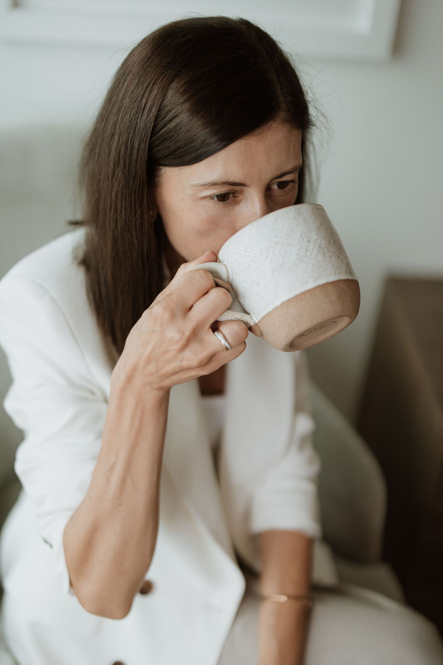 Close-up of ceramic coffee mug being held while sitting in cozy chair.
