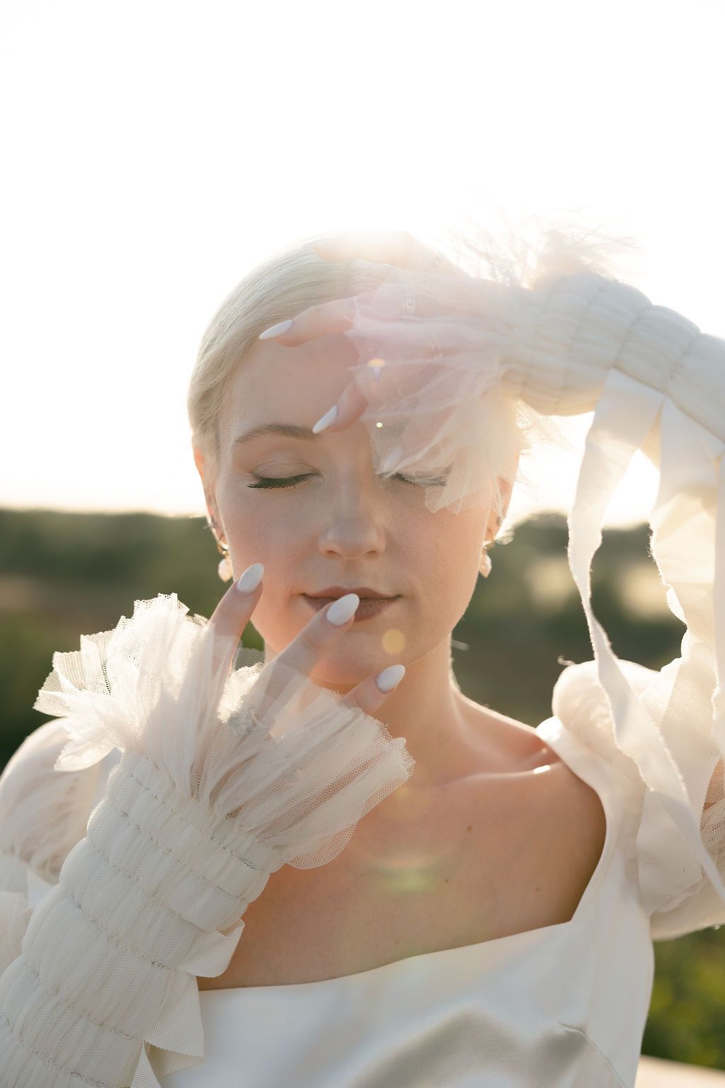 Ethereal bridal portrait with delicate tulle gloves and soft sunlit glow during golden hour.