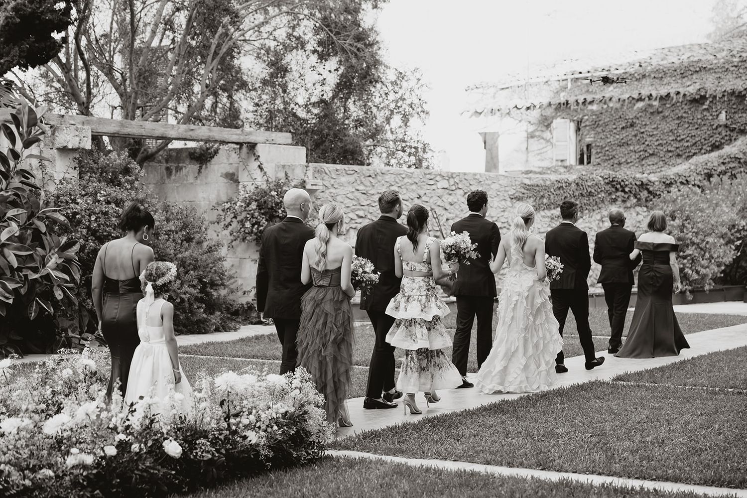 Black and white panoramic view of wedding guests gathering outdoors for a celebration.
