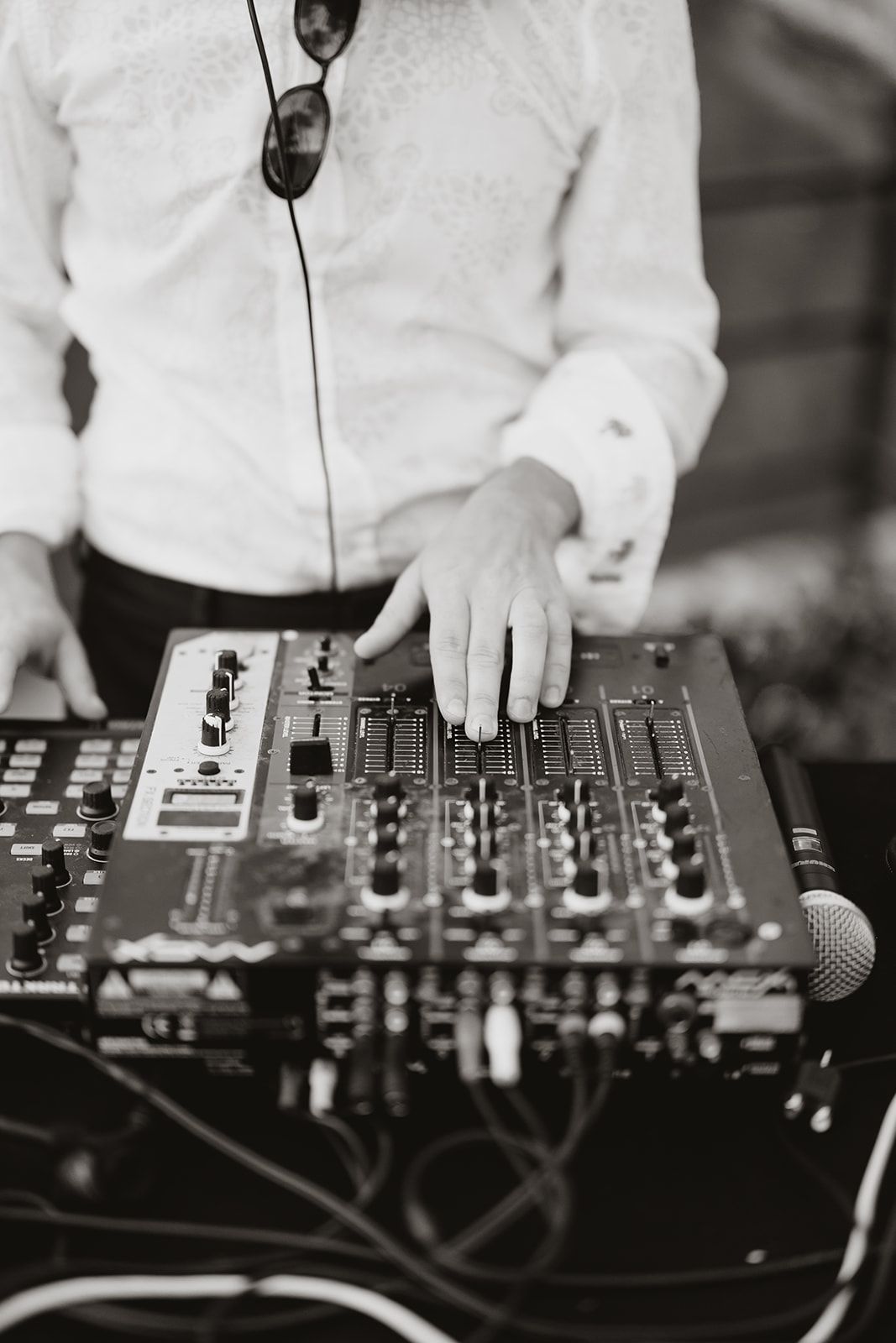 Close-up of DJ equipment and mixer controls in black and white.
