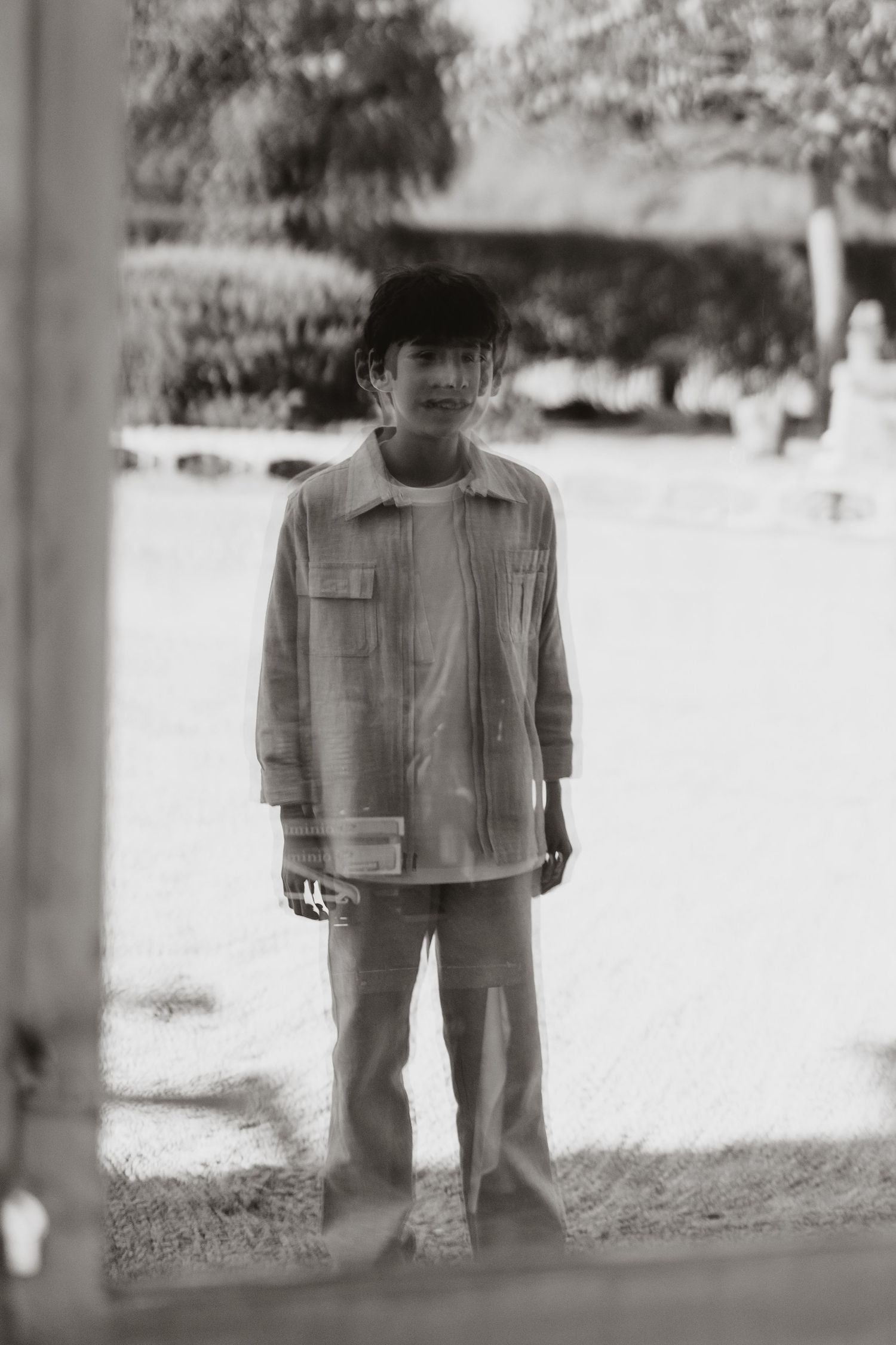 Vintage black and white photo showing someone wearing a light-colored jacket and pants standing in an outdoor setting.