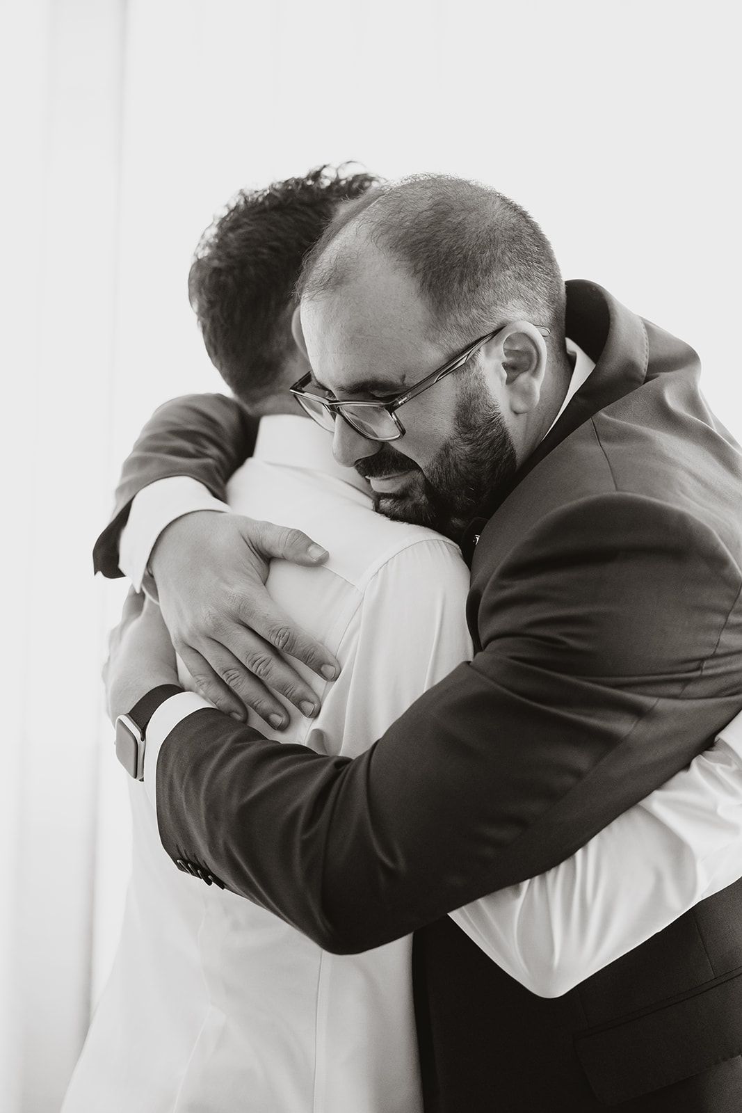 Two people share an emotional embrace in black and white photography.