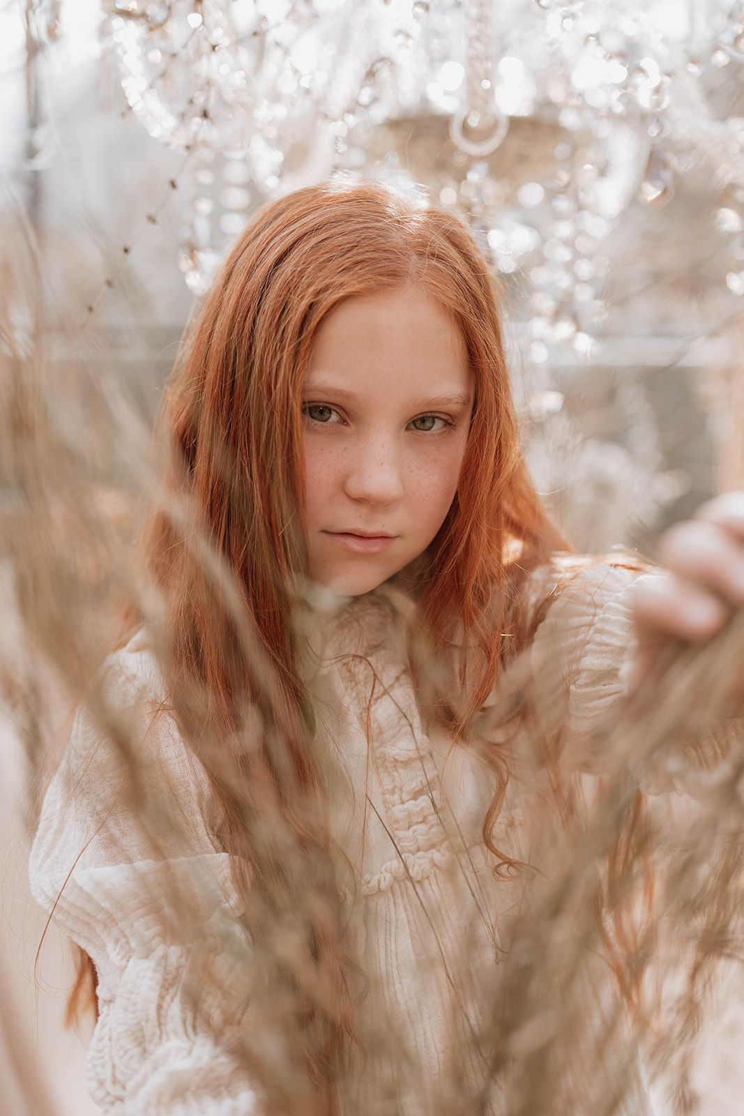 Artistic portrait framed by dried winter grasses in muted warm tones.