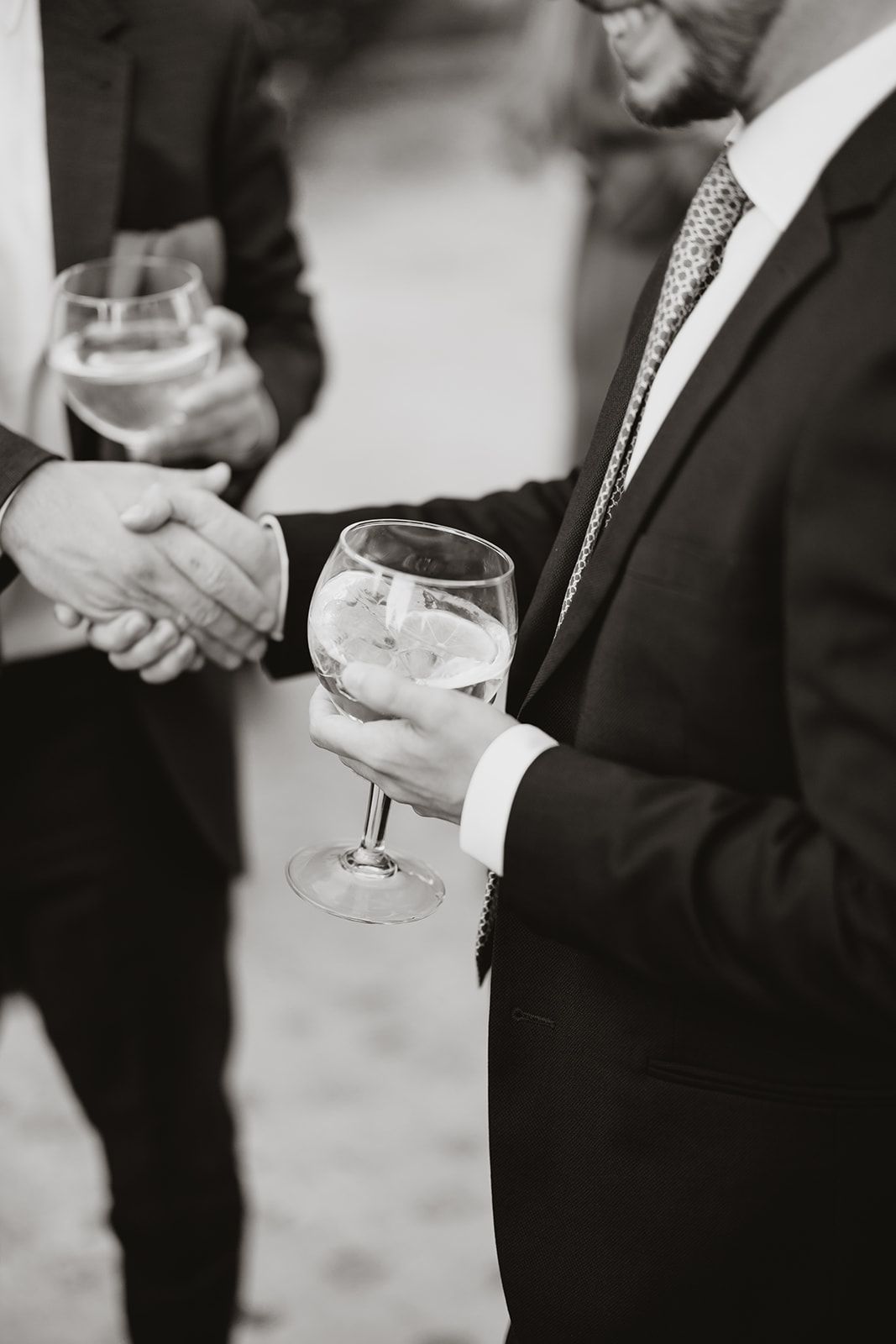 Black and white photo of guests holding wine glasses at formal reception.