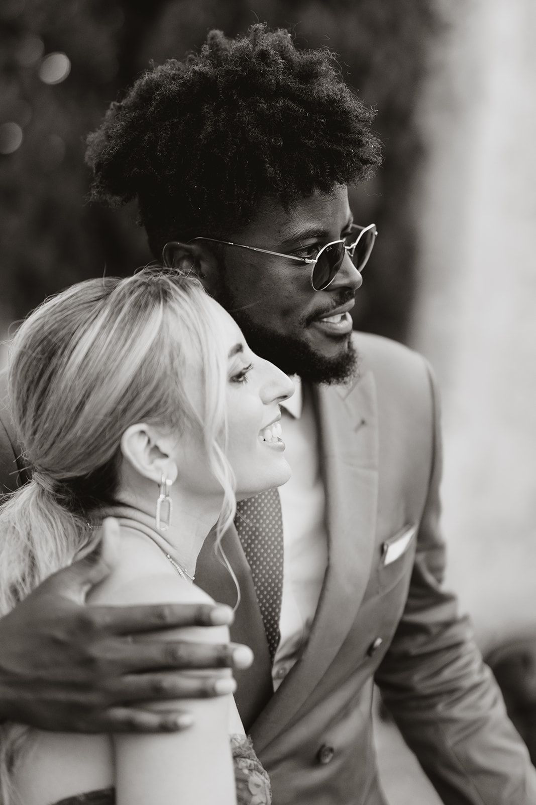 A joyful couple sharing a candid moment at a formal event, with a soft black and white aesthetic.