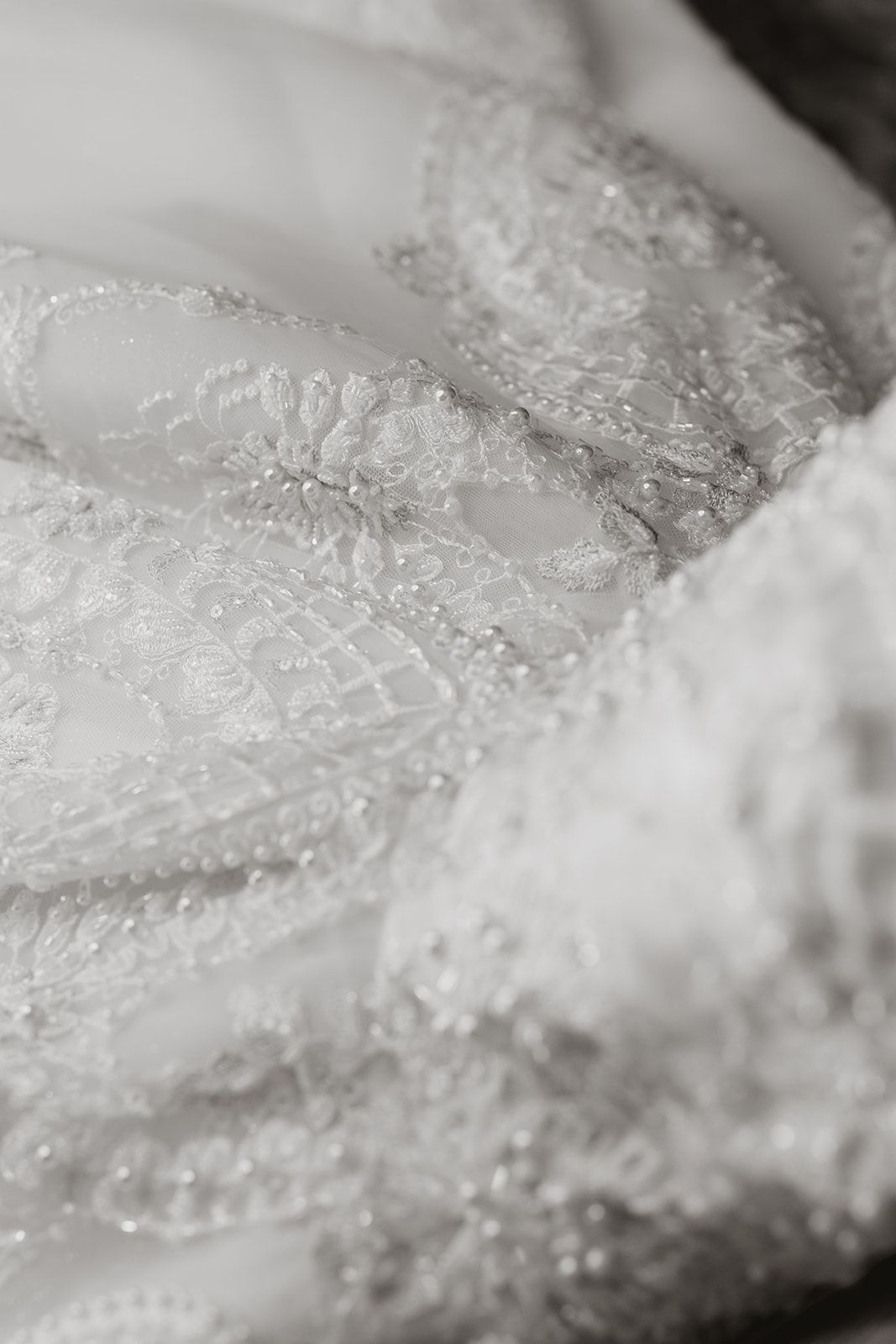 Detailed macro shot of intricate lace patterns on white wedding dress fabric.