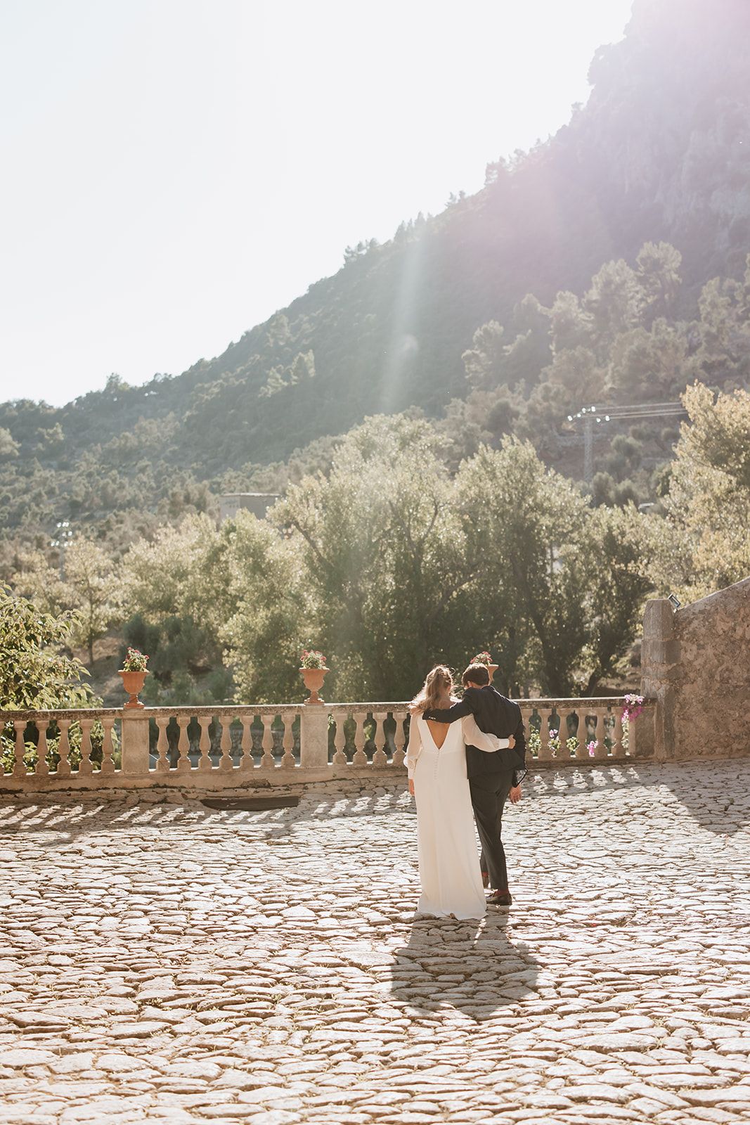 Couple dancing on a stone patio with sunlit mountain backdrop.