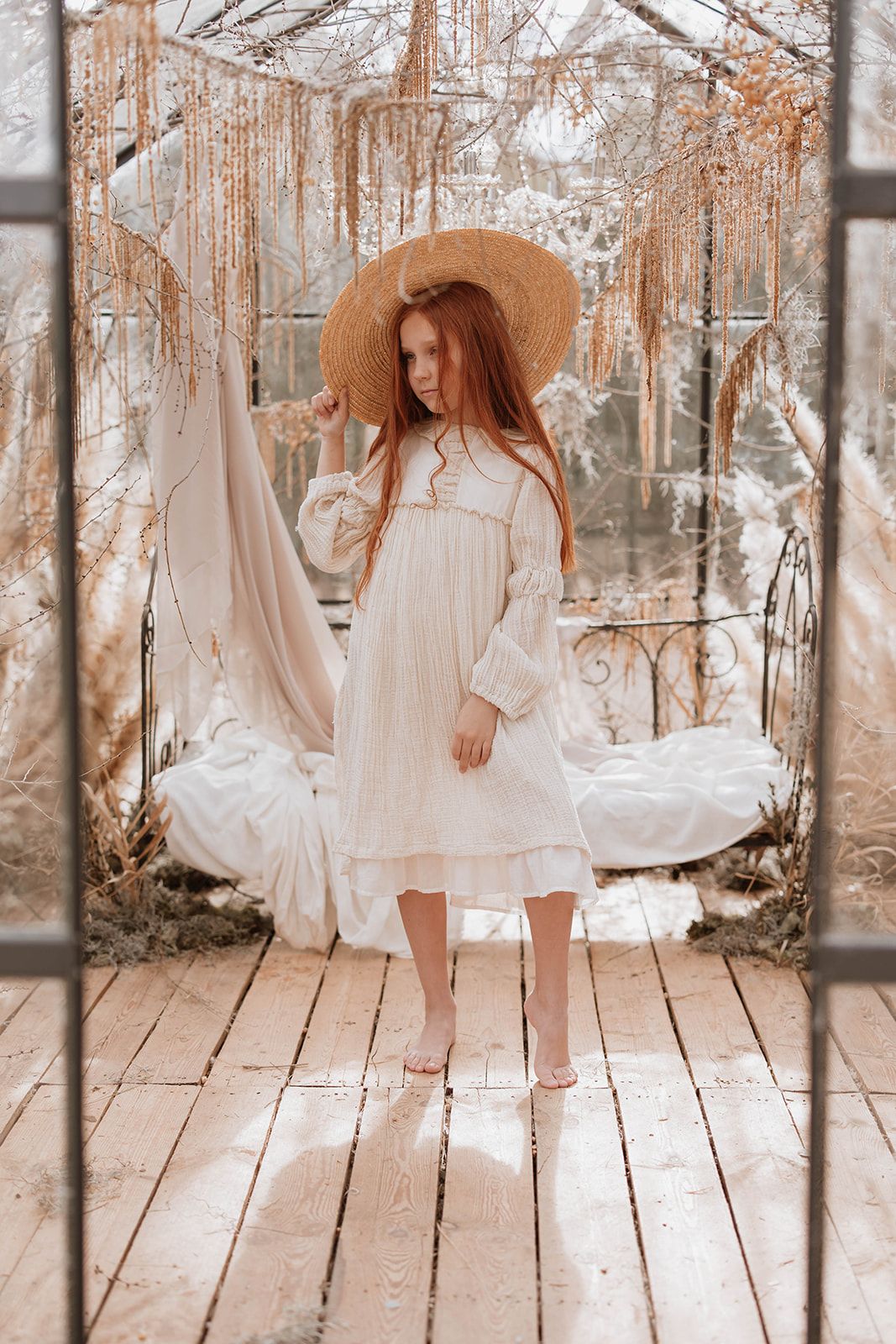 Dreamy outdoor scene with vintage dress and straw hat on wooden platform.