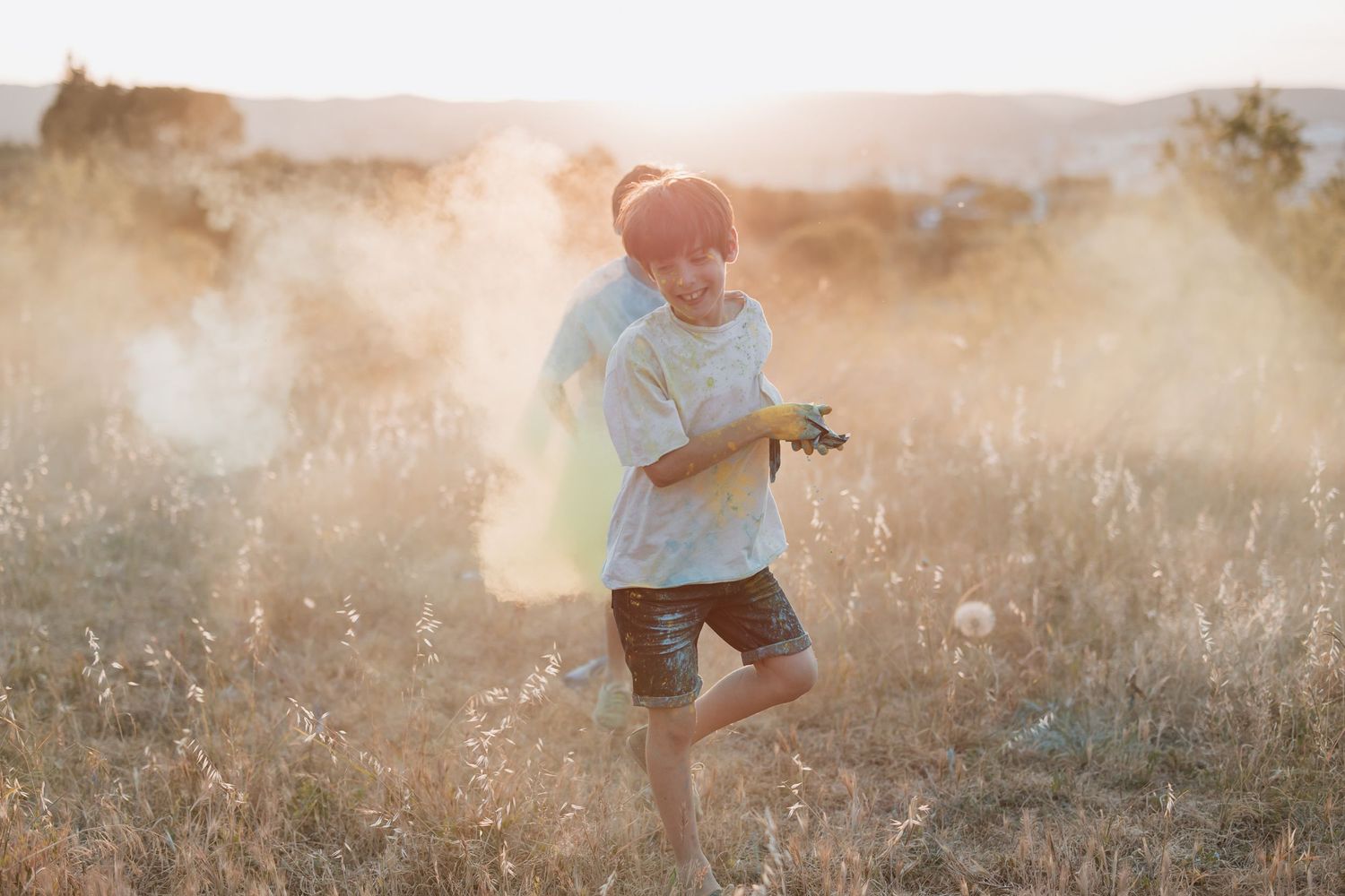 A person with a camera walks through a misty golden field at sunset, backlit by warm sunlight.