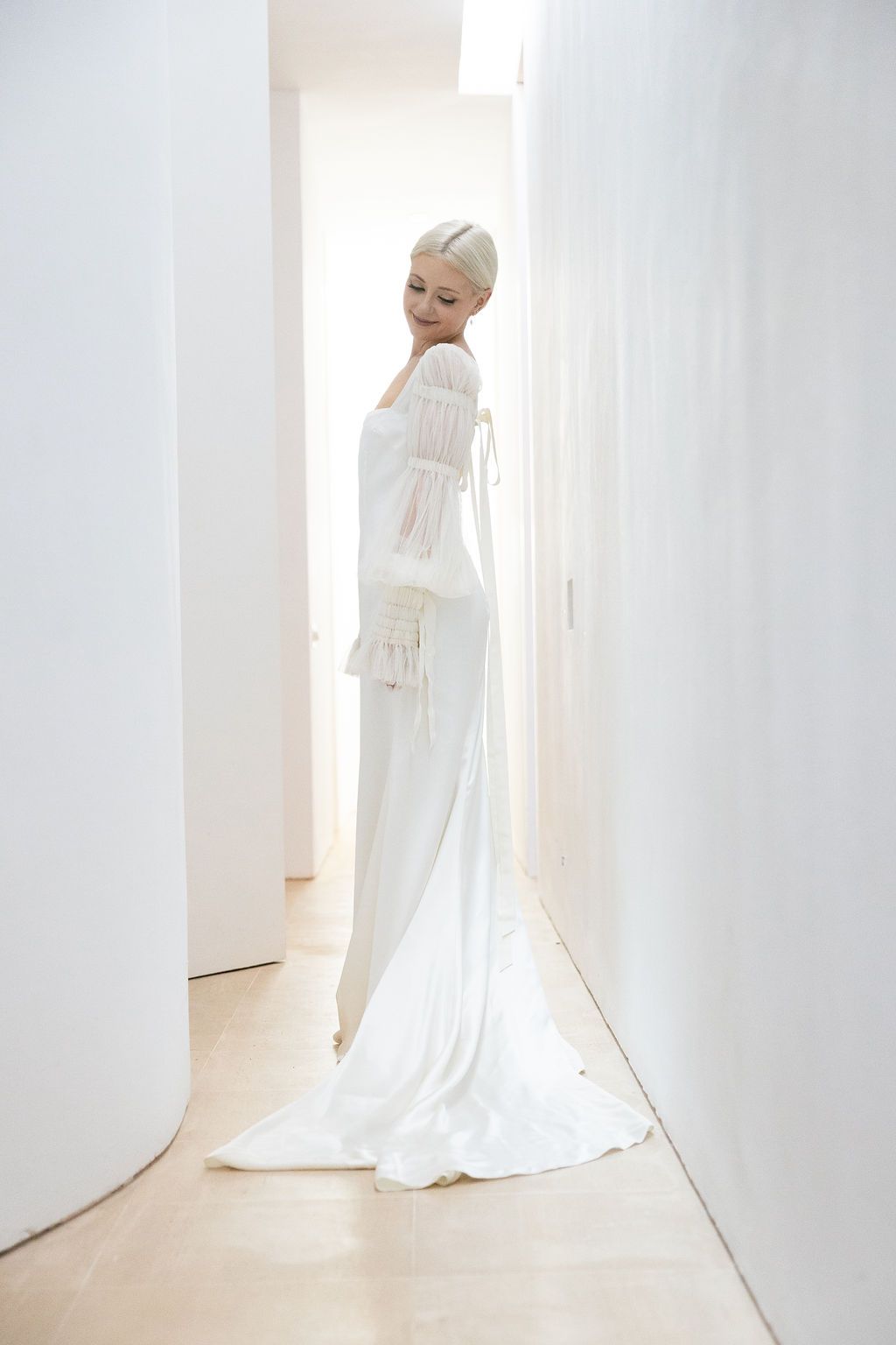 An artistic bridal portrait showcasing a sleek white gown with vintage-inspired details in a minimalist setting.