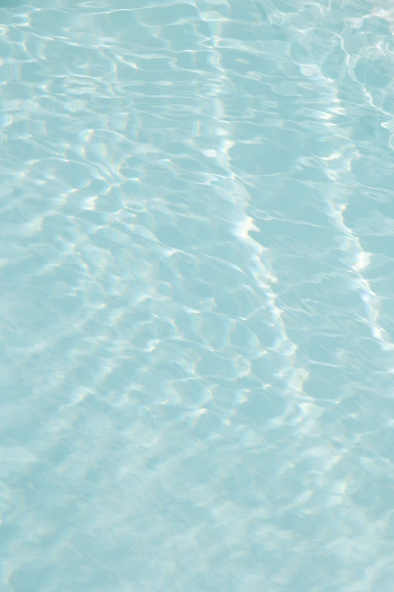Rippling turquoise pool water creating abstract light patterns on the surface.