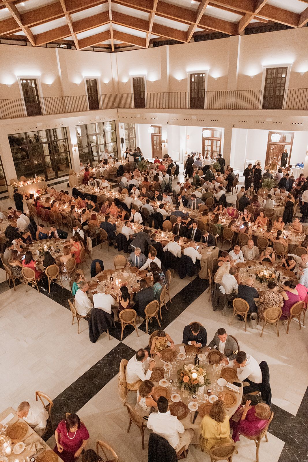 Elegant reception hall filled with round tables and guests during a wedding celebration.