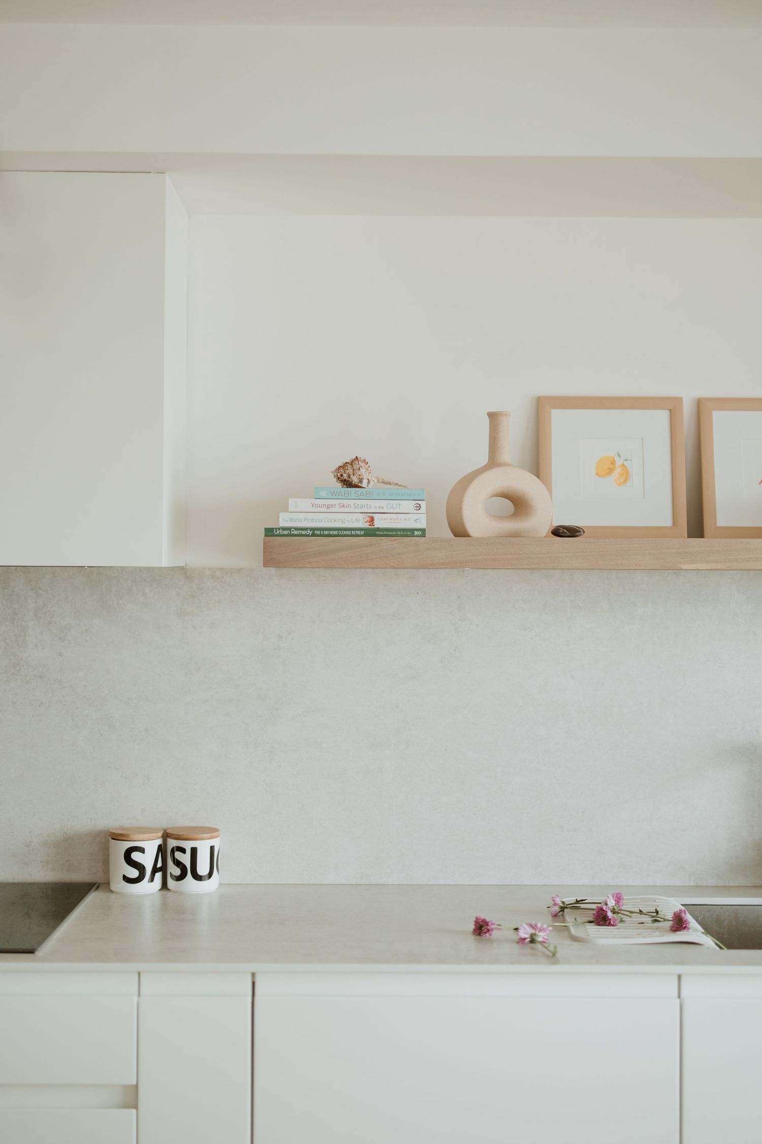 Minimalist white kitchen shelving with decorative items and artwork displayed.