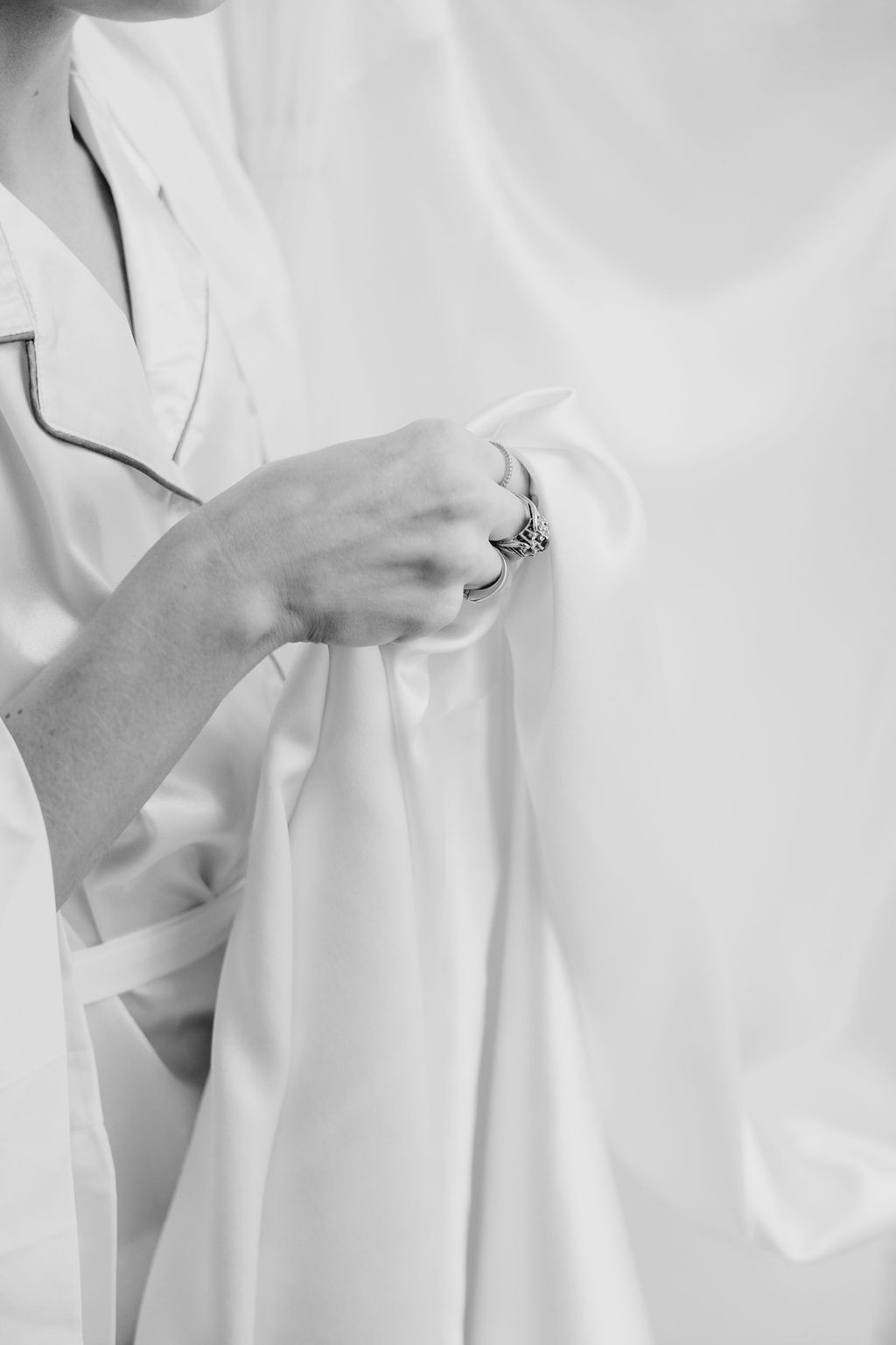 White silk robe with delicate jewelry detail against light background.