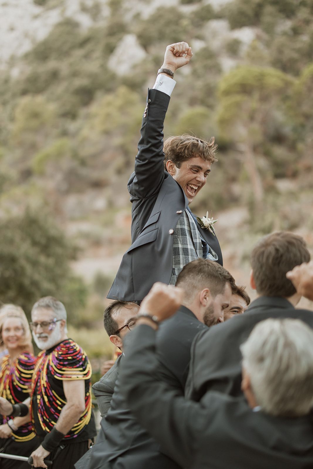 A celebrating guest is lifted up by the crowd at an outdoor wedding reception.