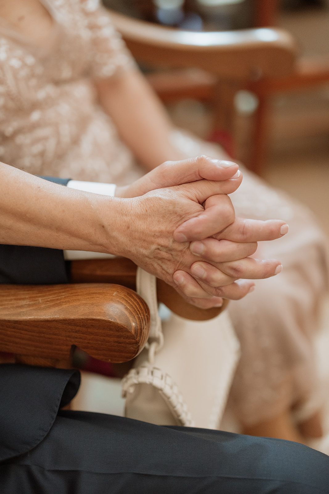 Close-up of clasped hands during intimate wedding ceremony moment.