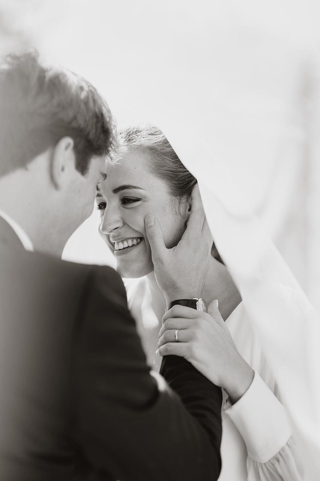 Black and white wedding portrait capturing genuine laughter between newlyweds.