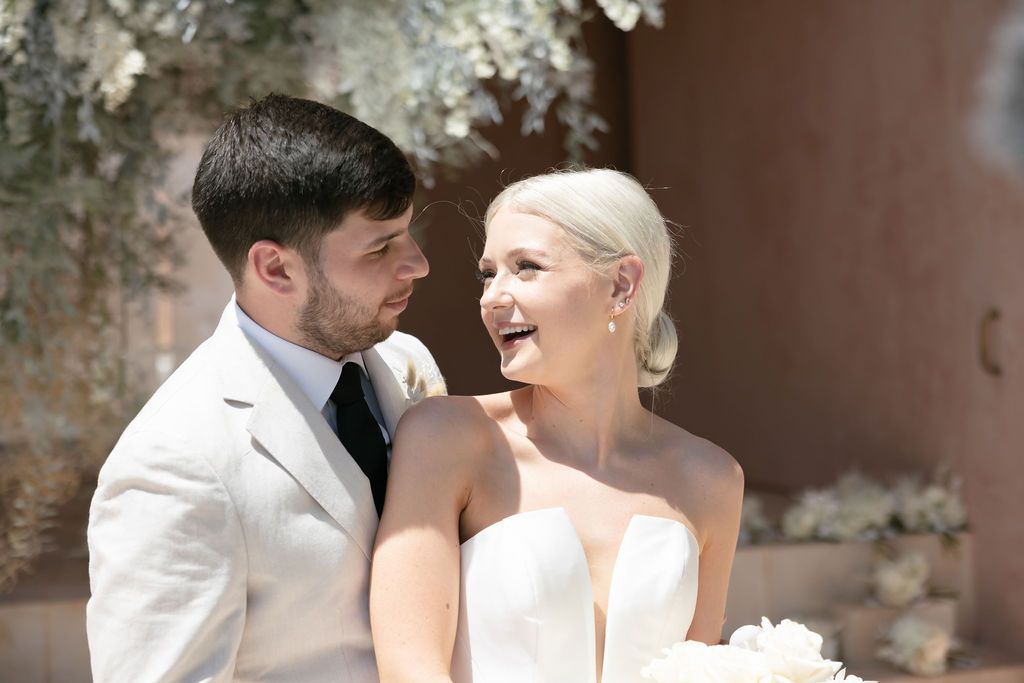 An intimate moment between newlyweds under a floral arrangement.