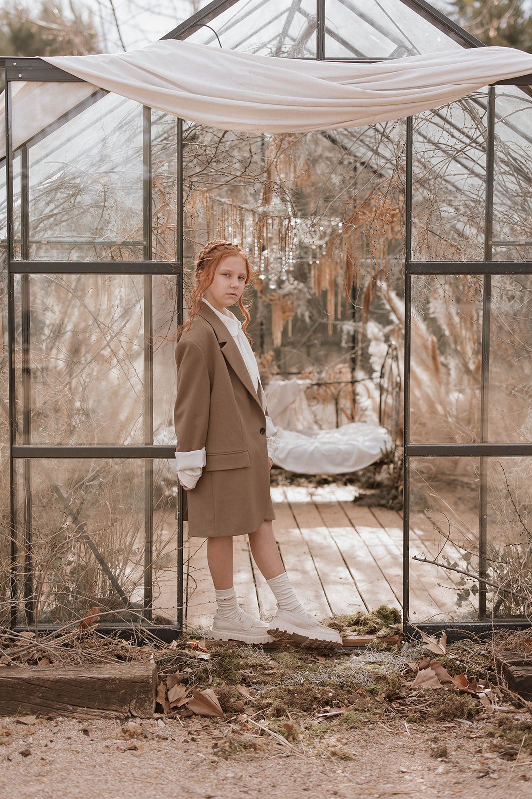 A dreamy greenhouse portrait featuring someone in vintage-style attire and white knee socks.