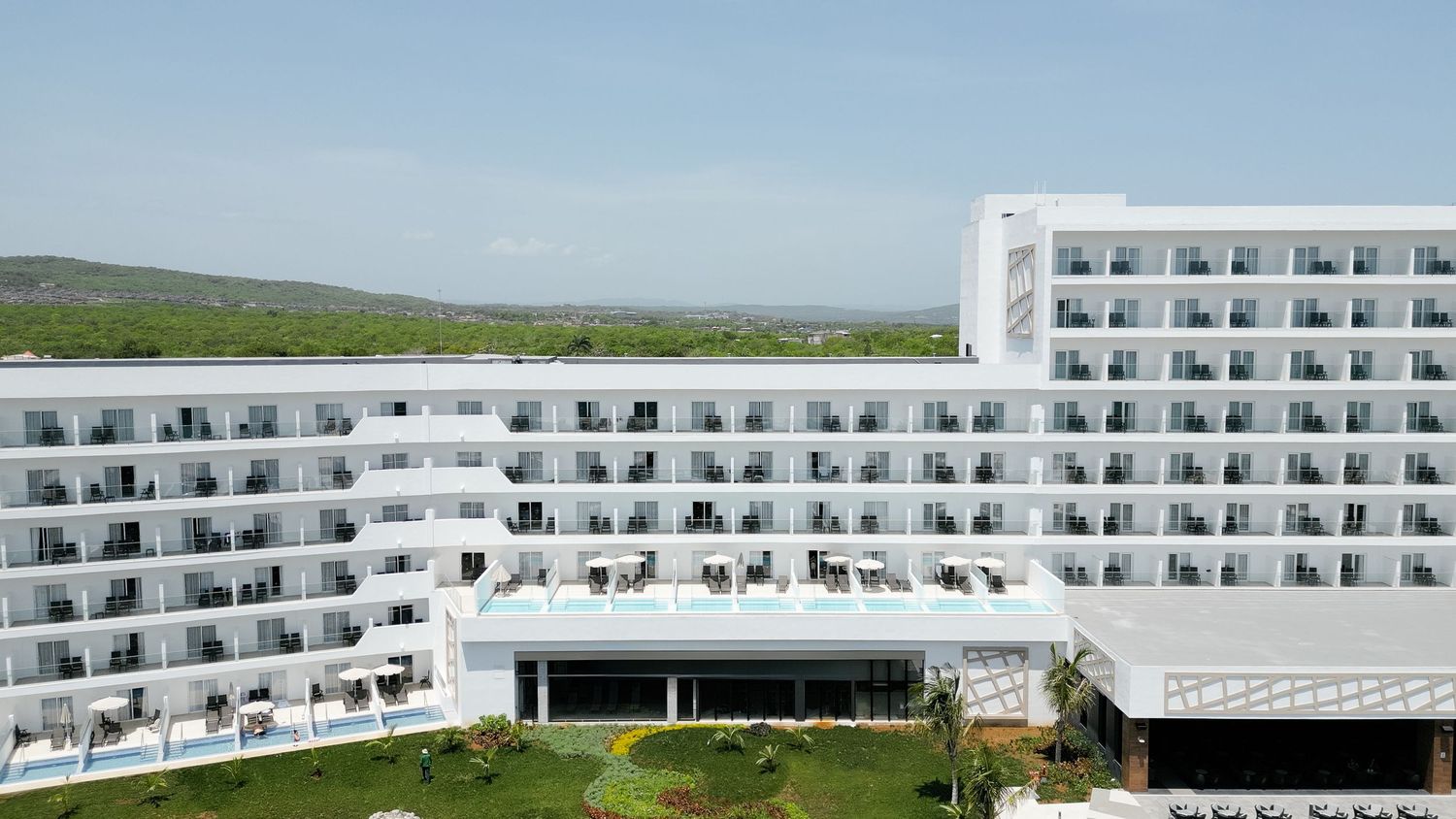 Angular white hotel building with repetitive balcony patterns and a modern architectural design.