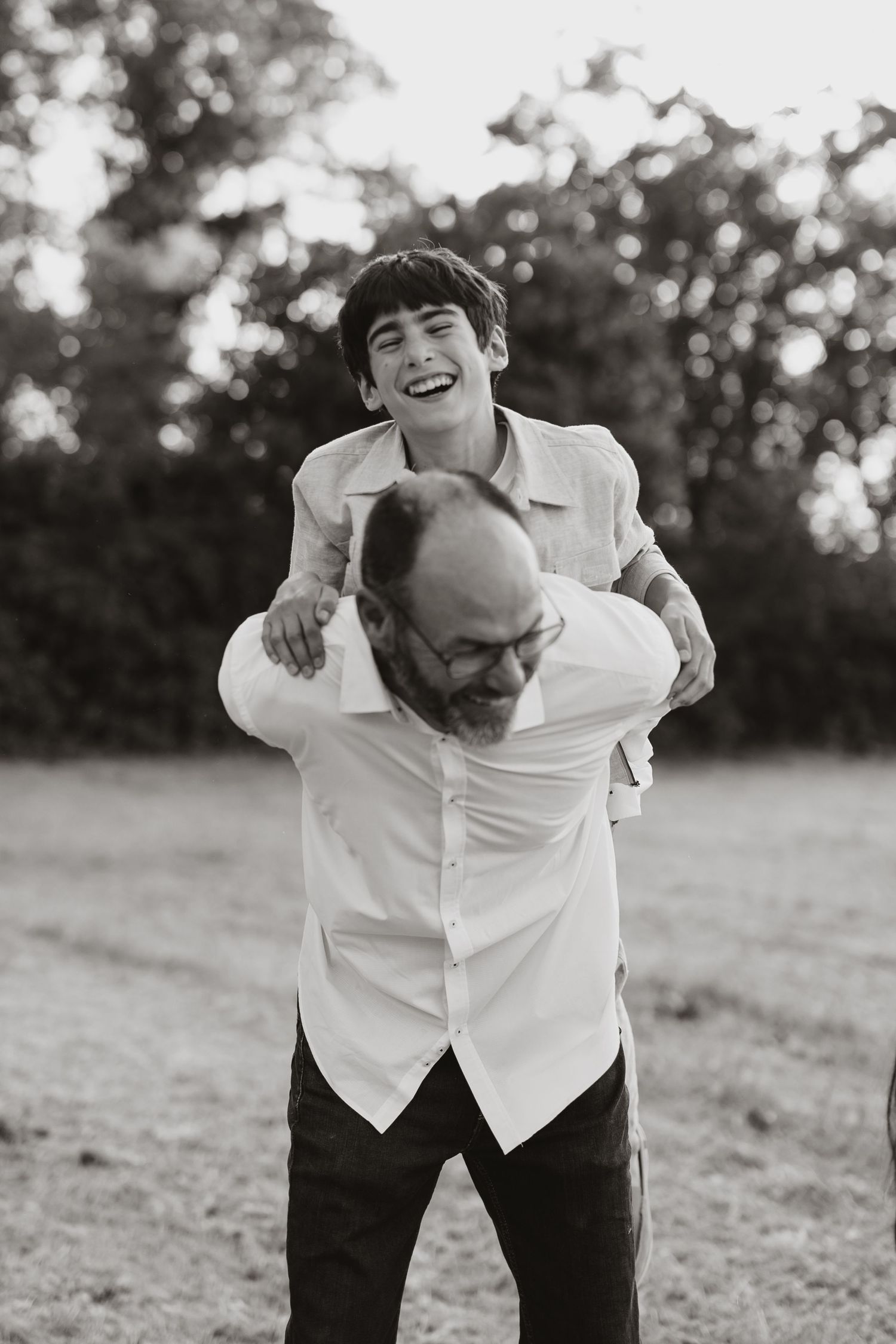 Black and white photo series showing joyful candid laughter and movement in an outdoor field setting.