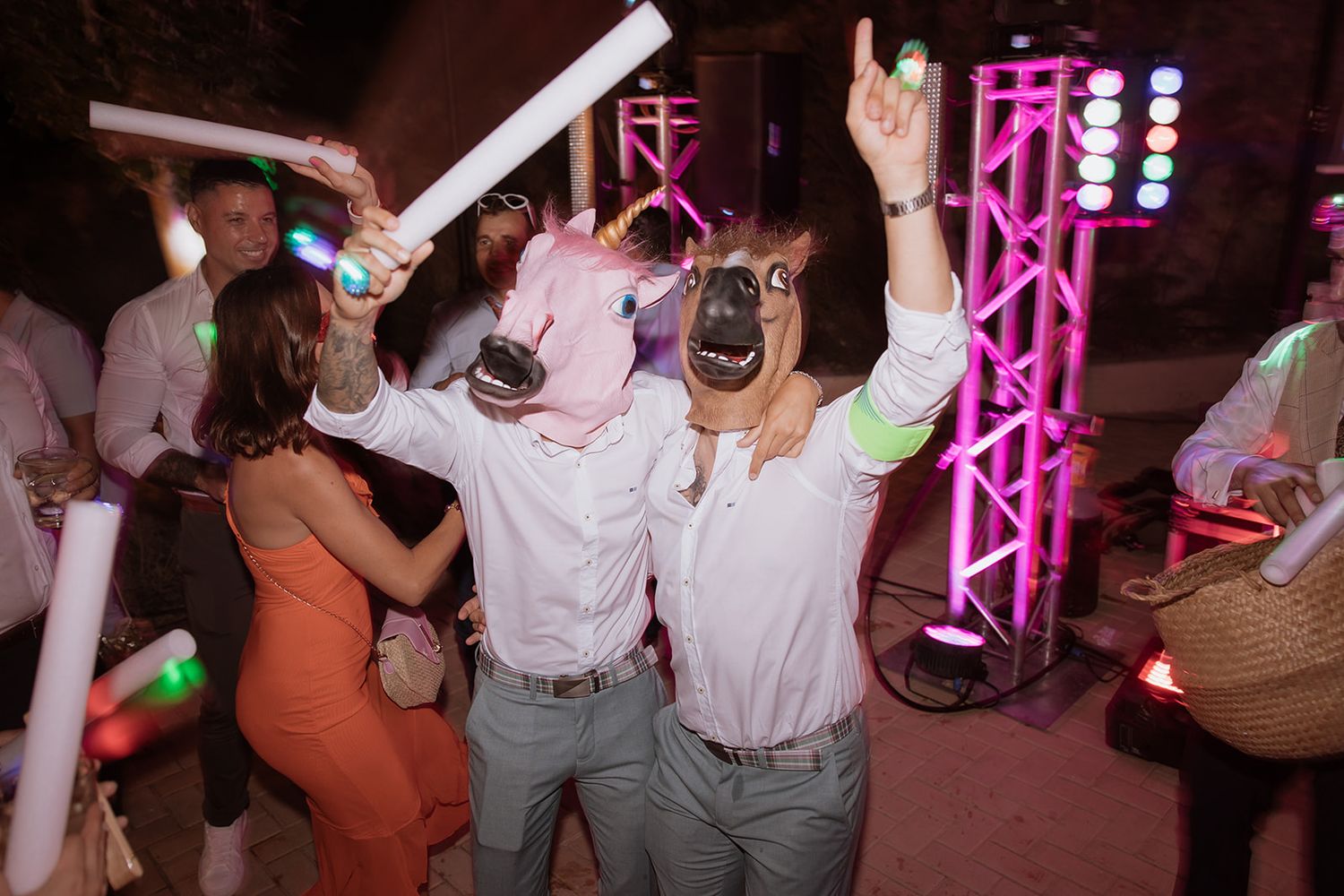 Wedding reception dance floor filled with guests under pink and purple lighting.