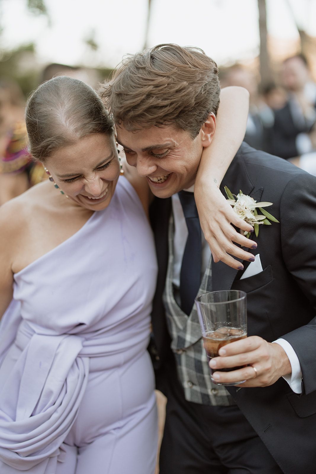 A tender moment shared between wedding guests as they embrace and smile together.