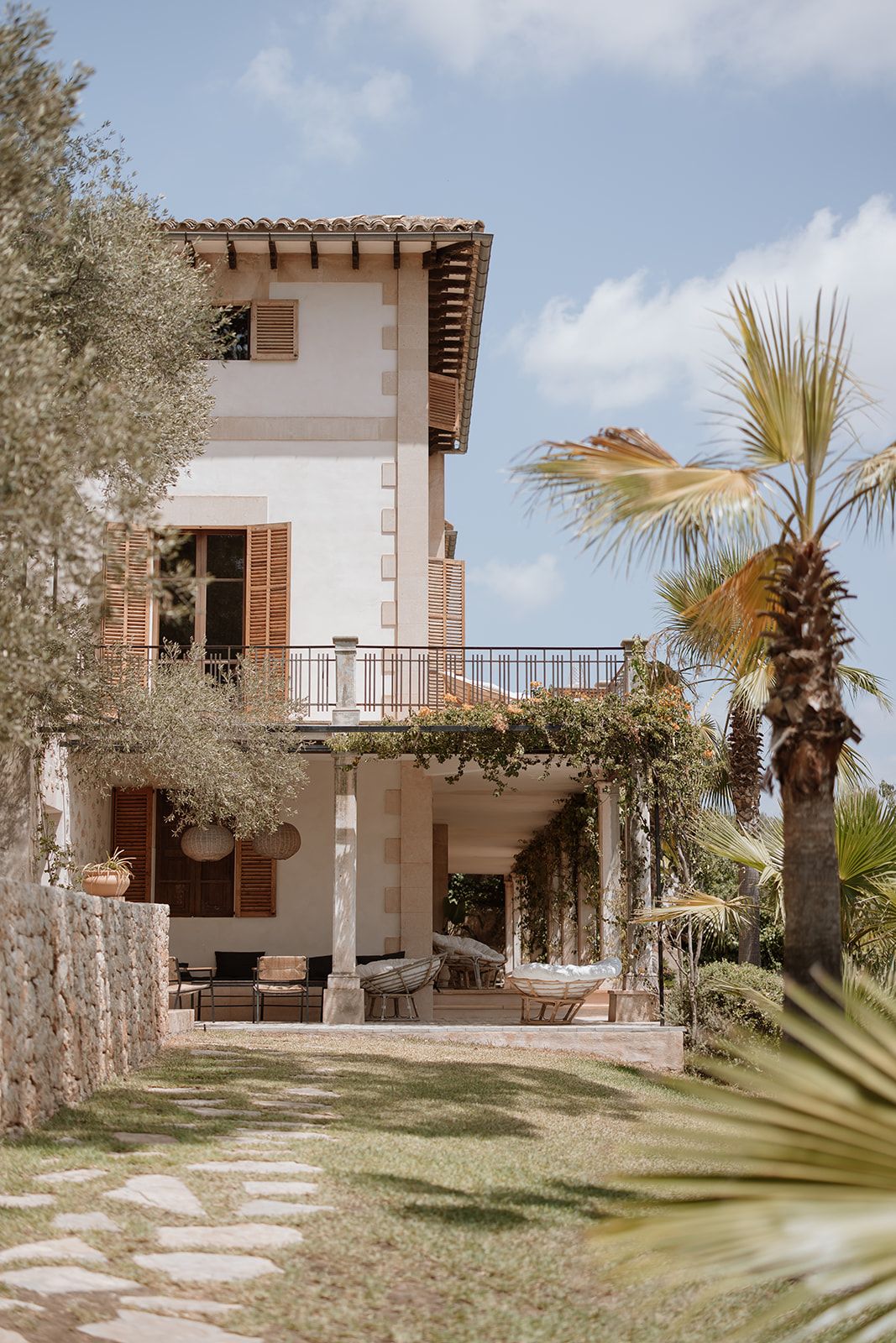 Mediterranean-style villa with palm trees and stone pathways in the garden.
