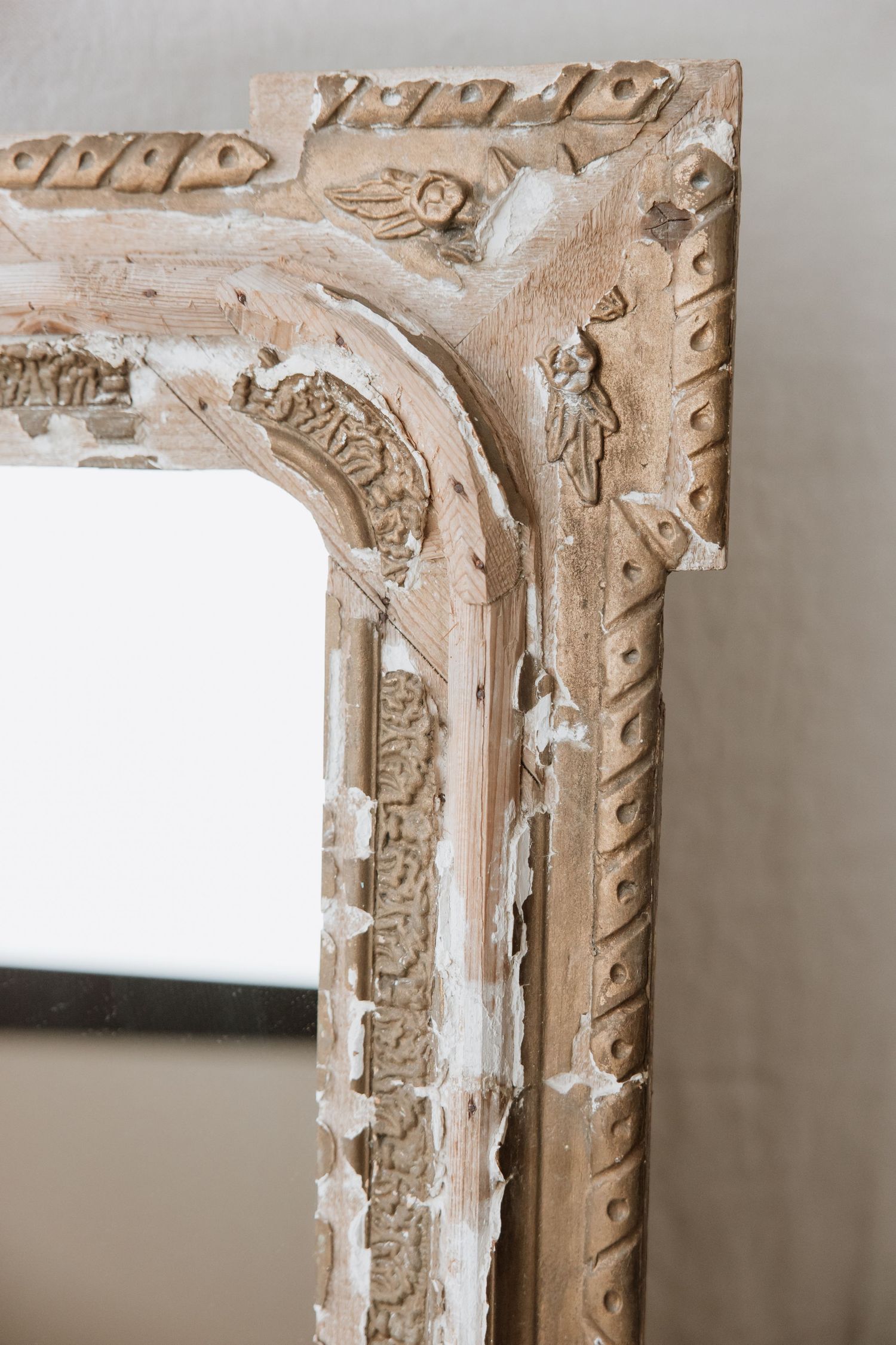 Close-up of an ornate vintage mirror frame with detailed carved patterns.