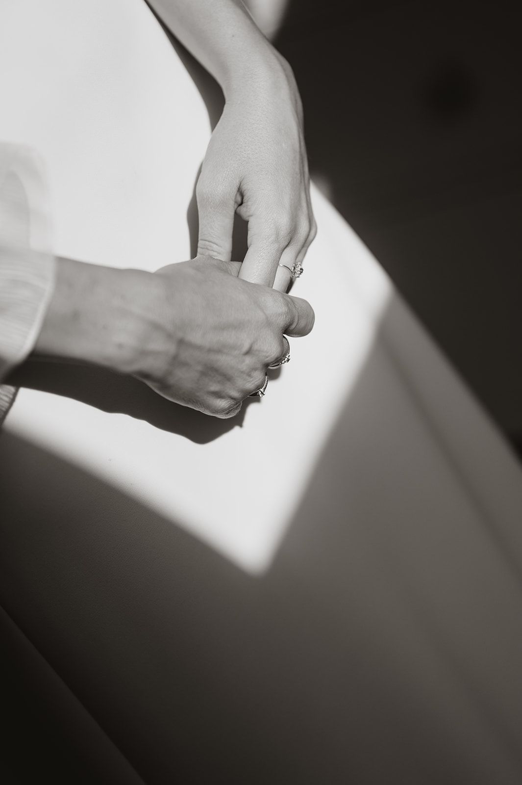 Black and white artistic photo of hands adjusting wedding dress details.