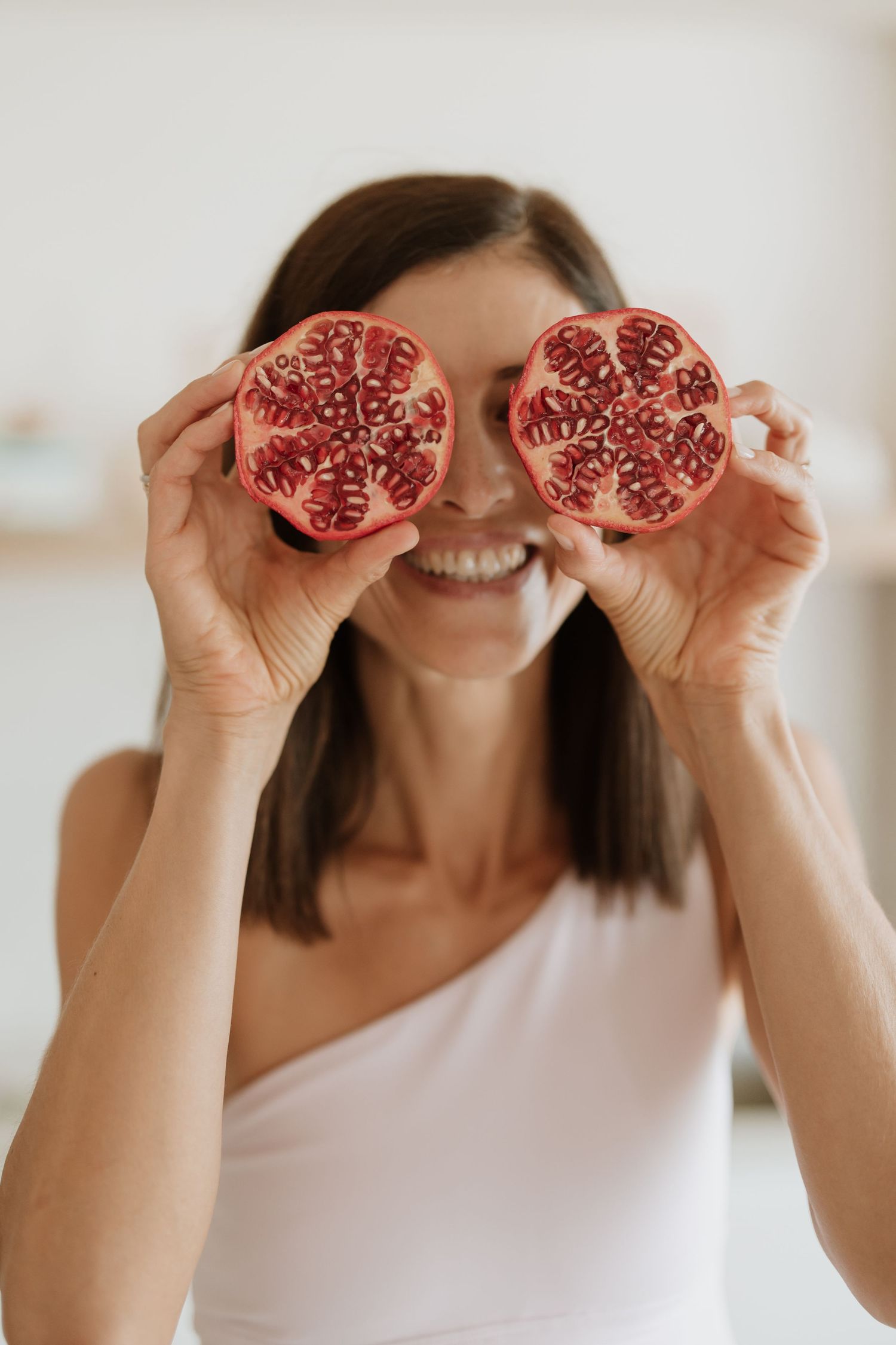 Fresh pomegranate halves held up against bright kitchen background.