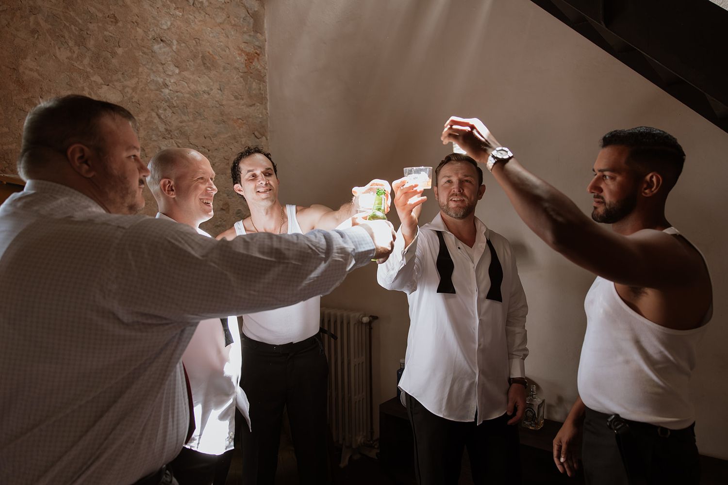 Group of friends in white shirts toasting together during celebratory moment.