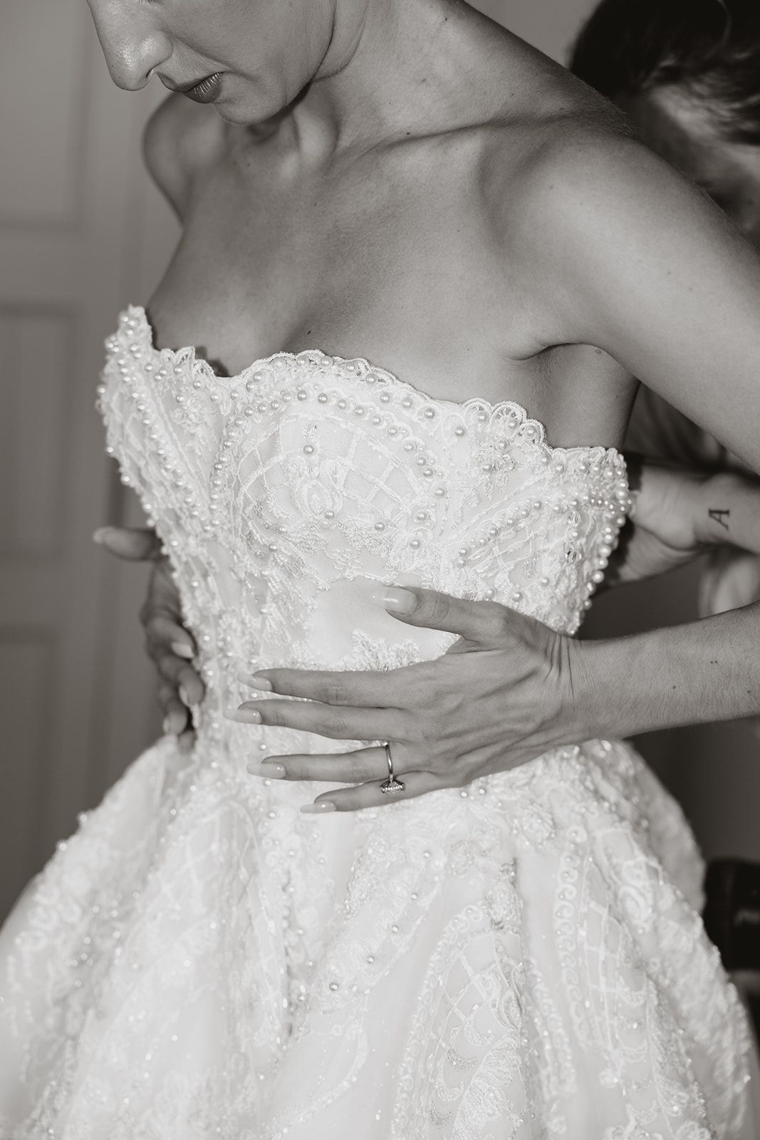 Close-up detail of wedding dress bodice showing intricate beadwork and lace.
